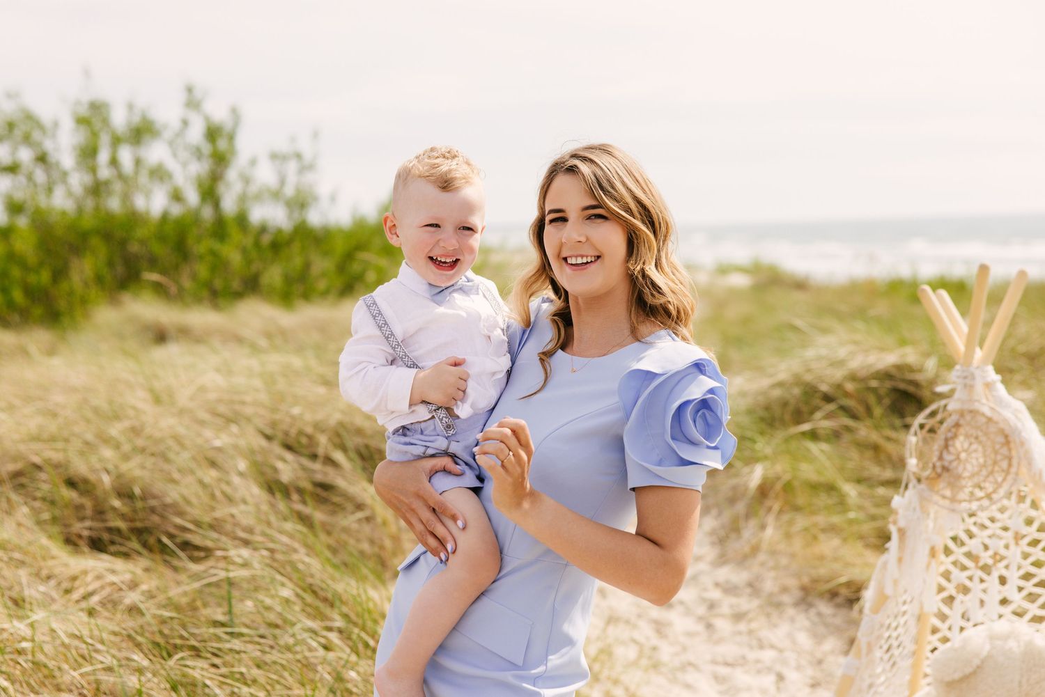A sunny beach portrait with coastal vegetation in the background.