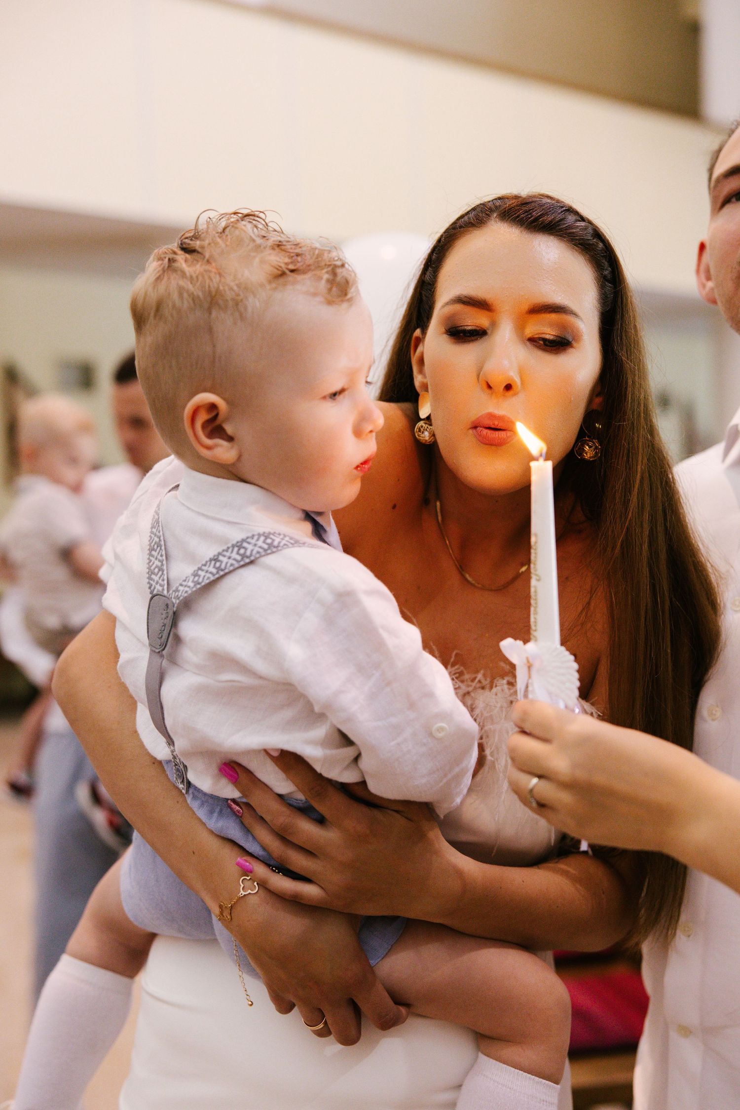 Baptism ceremony moment with candle lighting in white formal attire.