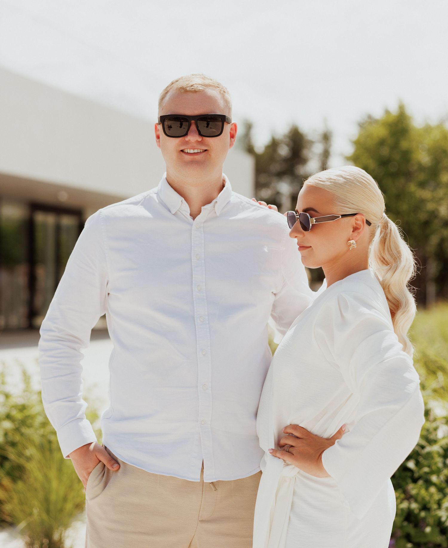 People dressed in crisp white outfits pose together outdoors on a sunny day.