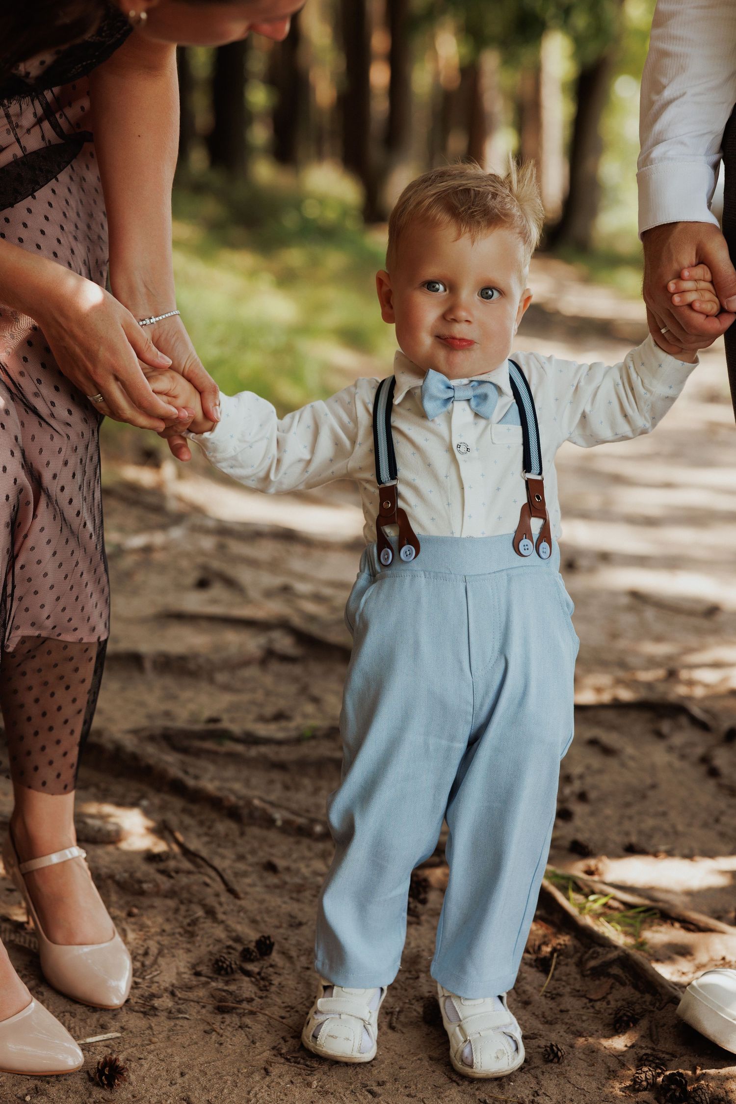 Close-up shots of small feet in light blue overalls walking on dirt ground in a forest setting.