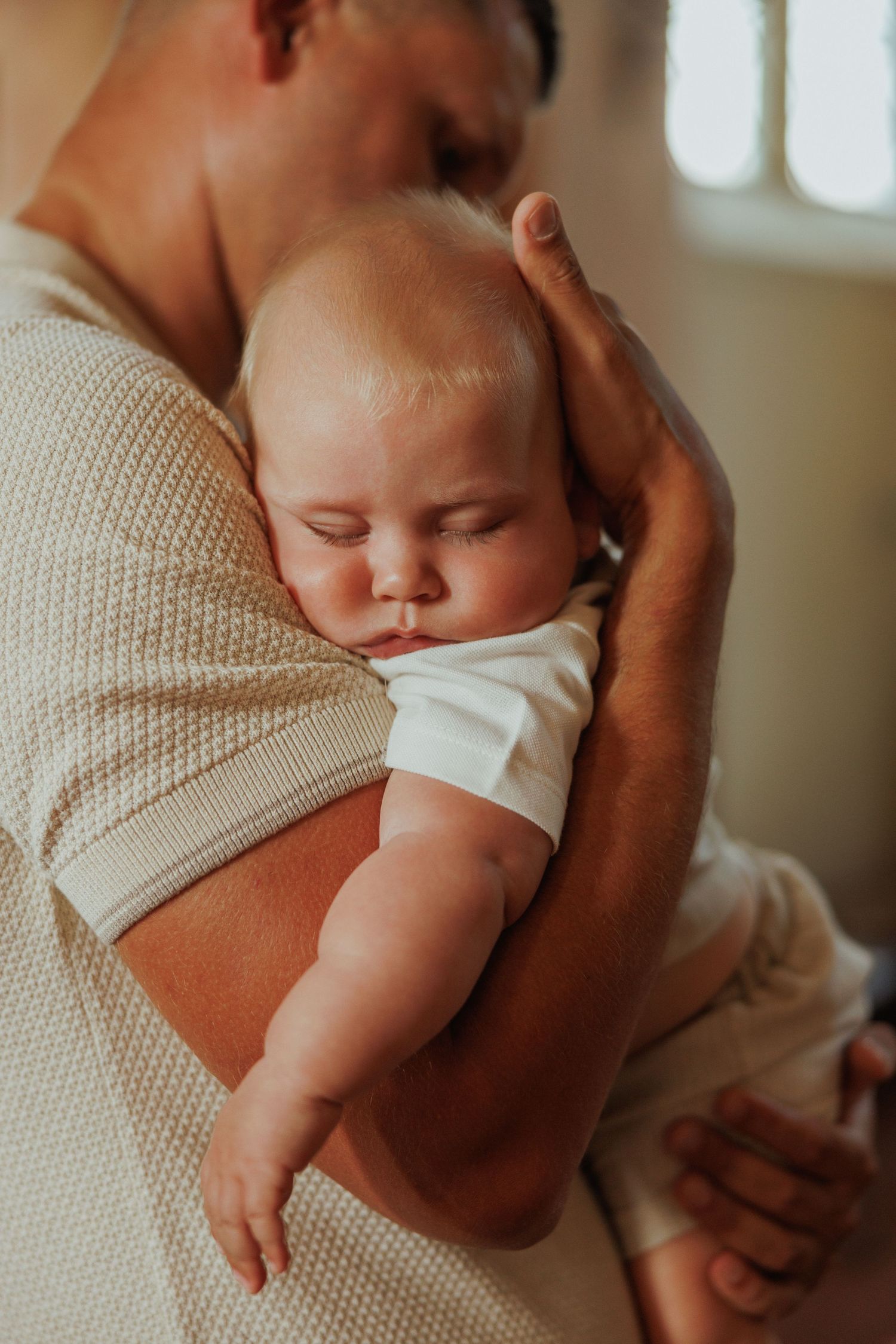 Close-up shot of a sleeping baby being cradled in soft beige knit fabric.