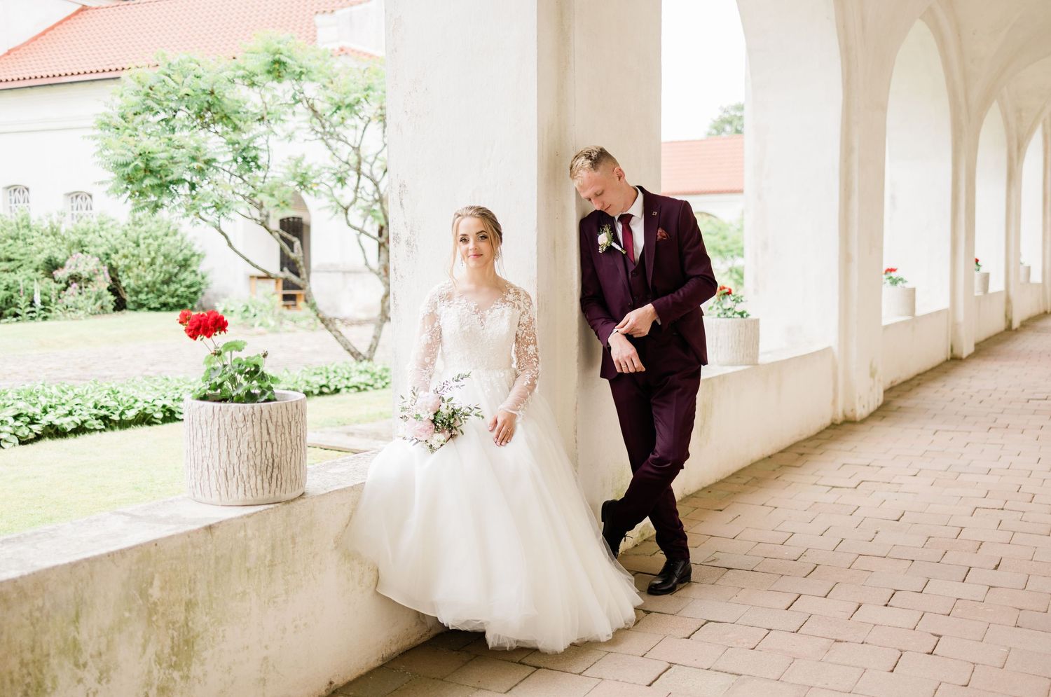 Romantic wedding sequence showing couple's interaction in sunlit colonnade with garden views.