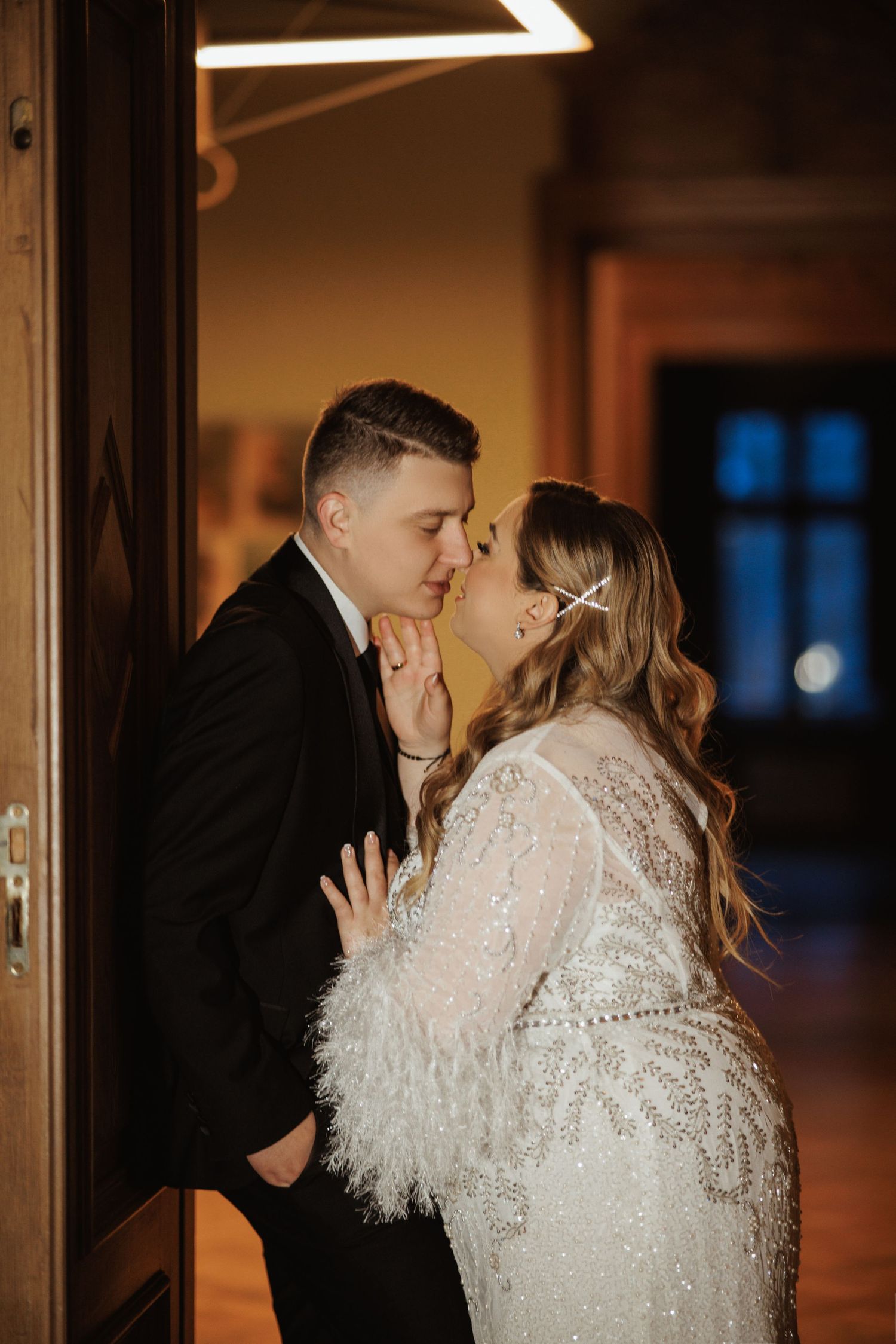 Romantic wedding couple poses in elegant hallway with wooden details.
