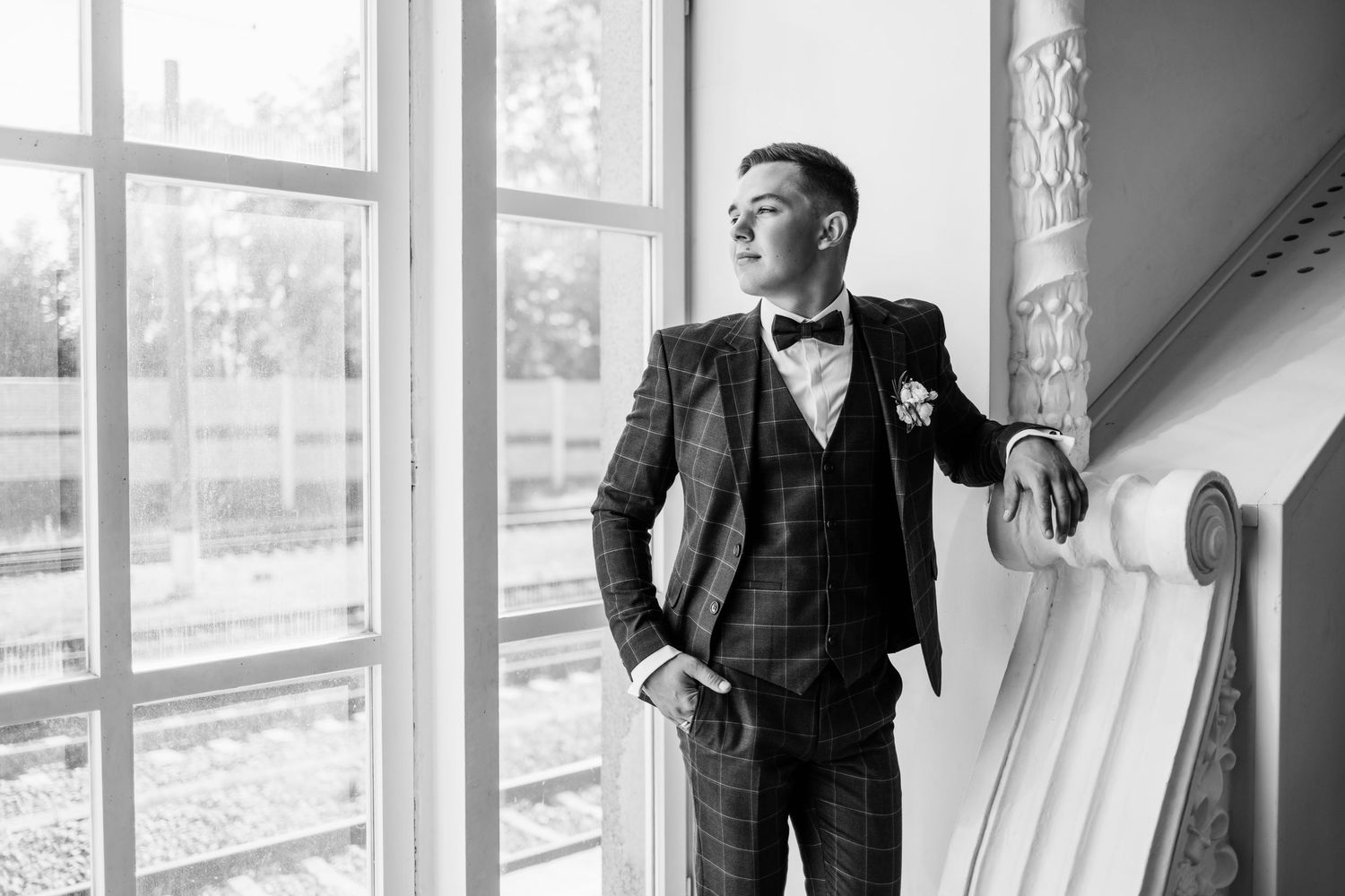 Black and white wedding portraits in a bright window-lit interior with classic formal attire.