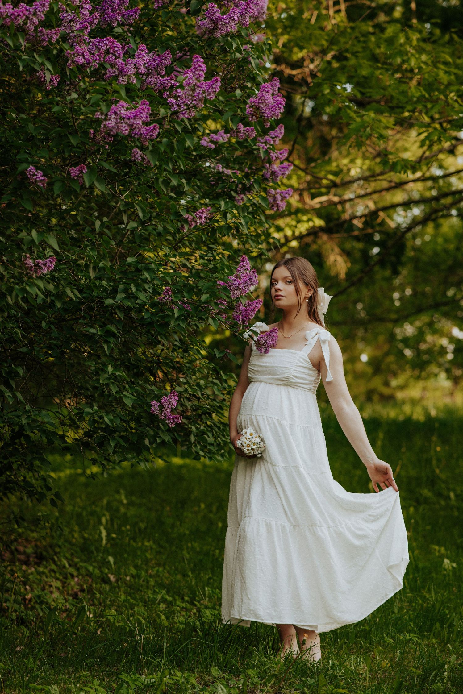 White sundress against blooming lilac bushes in a garden setting.
