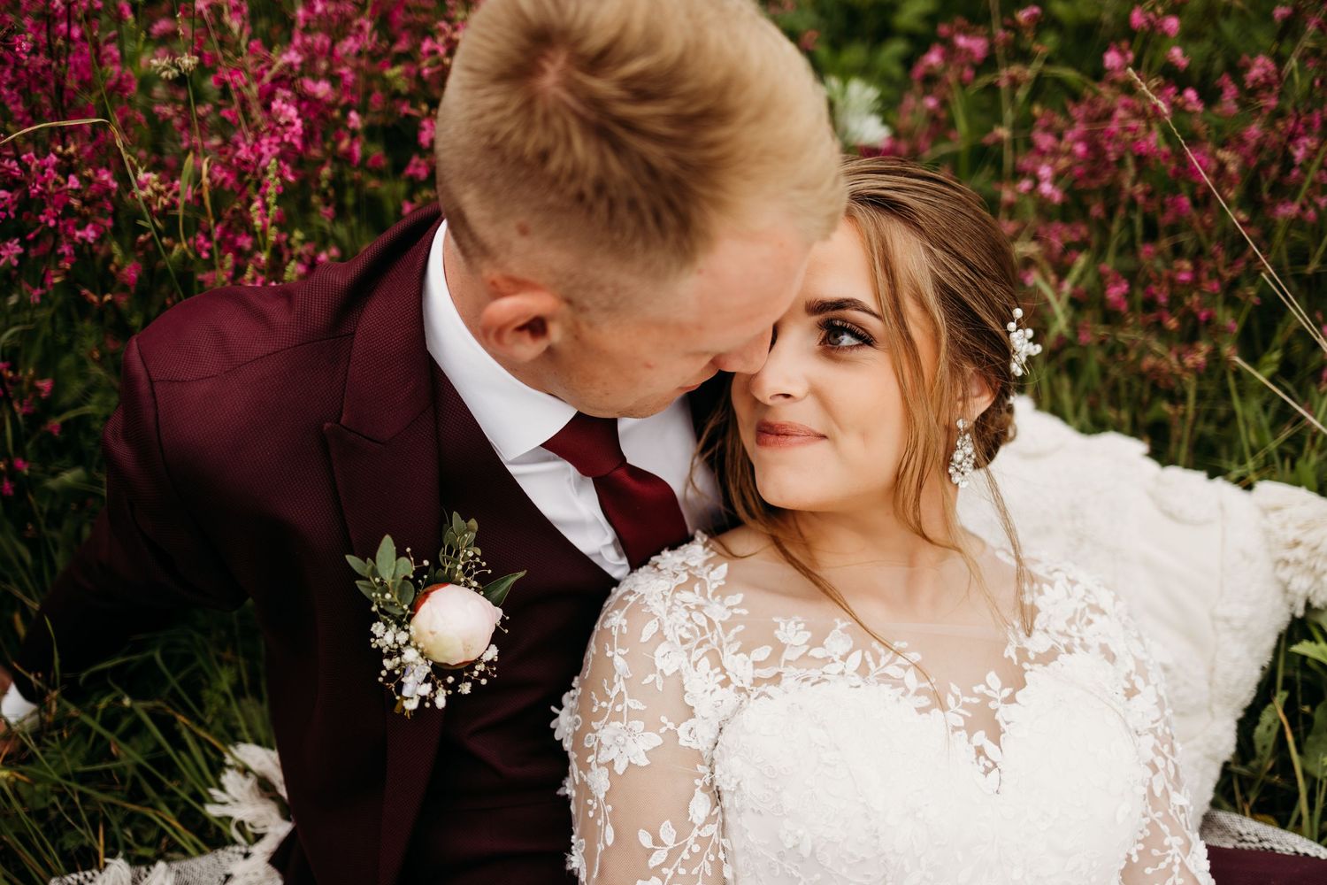 Wedding portrait of couple sharing intimate moment among pink flowers.