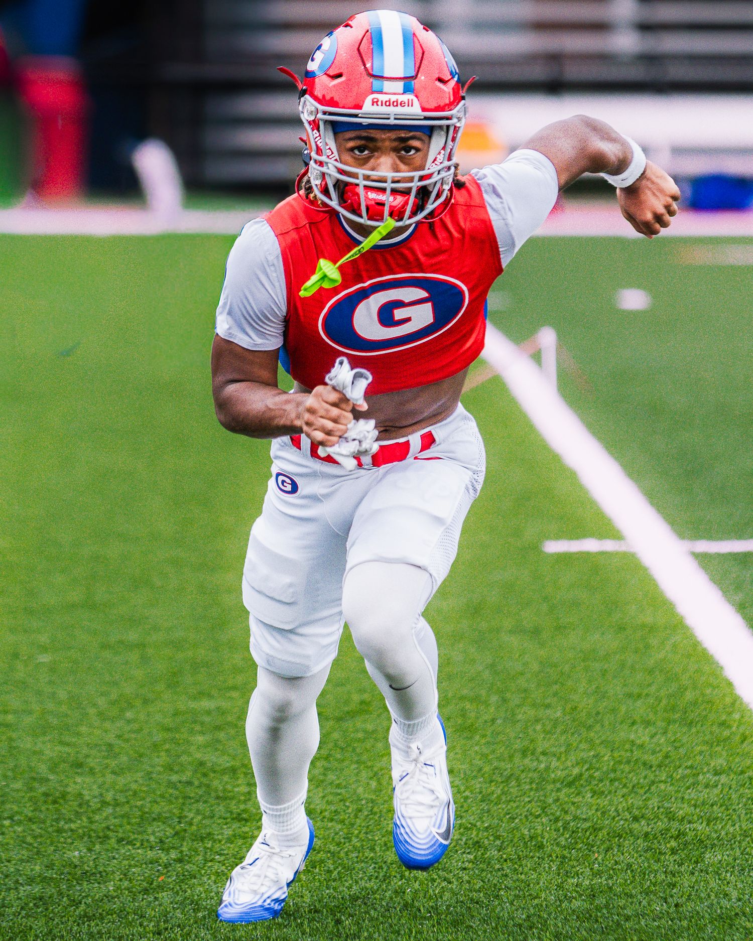 Football players in red and white uniforms practicing running drills on the field.