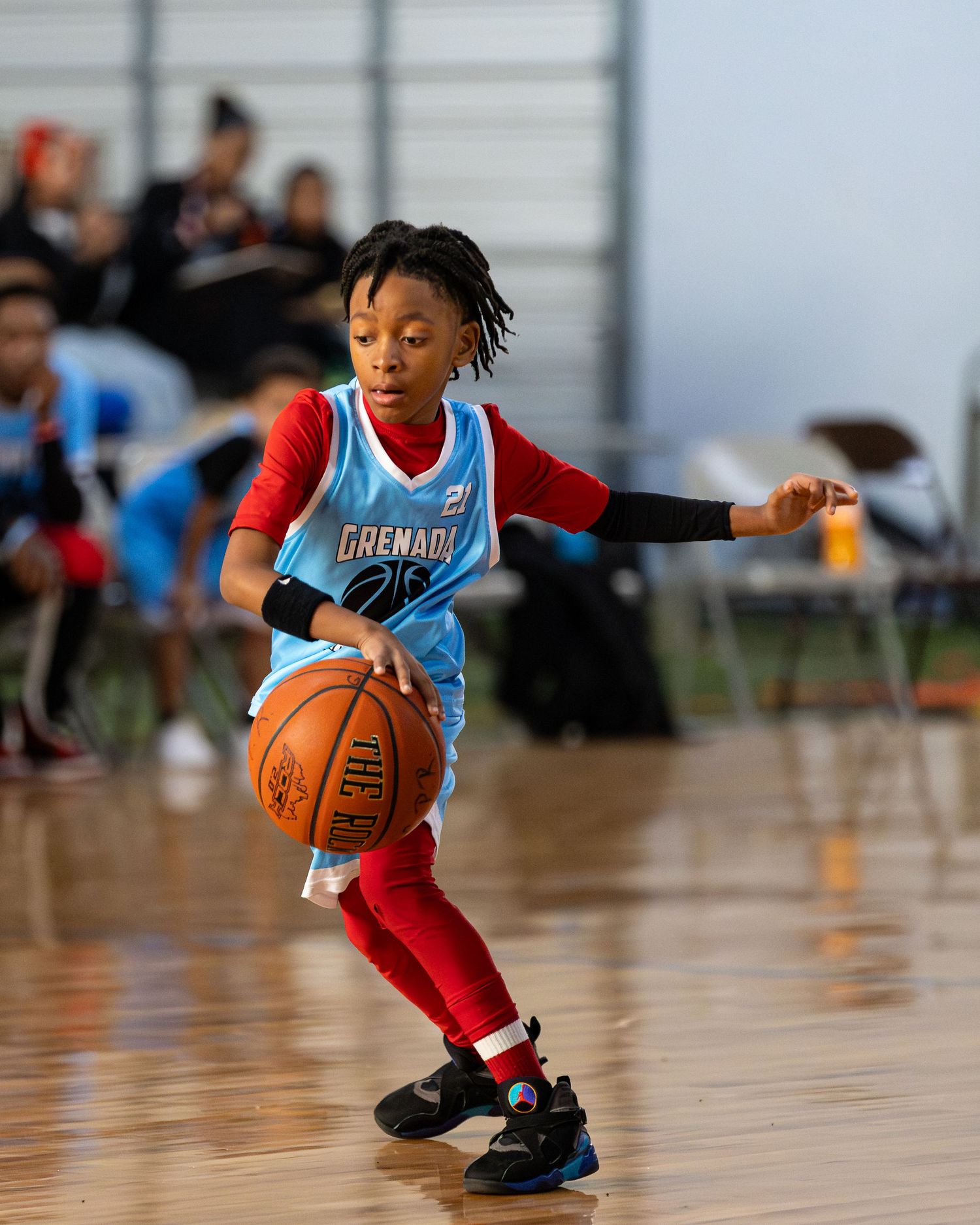 Young basketball player dribbles low while making quick moves on the shiny hardwood court during practice.