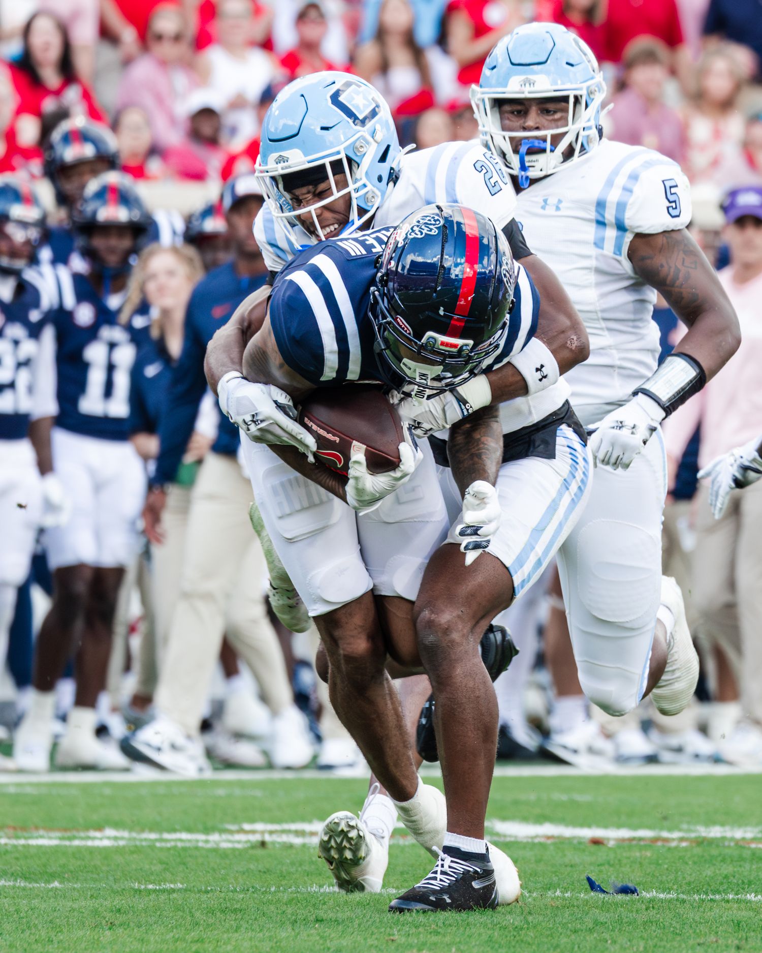 College football players in white uniforms scramble for possession of the ball during an intense game play.