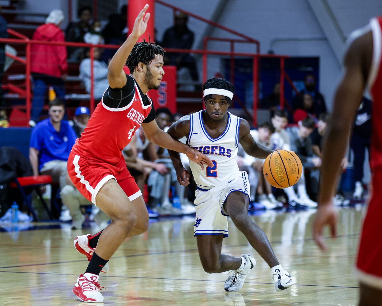 A basketball game in progress with players from opposing teams in red and white uniforms competing on the court.
