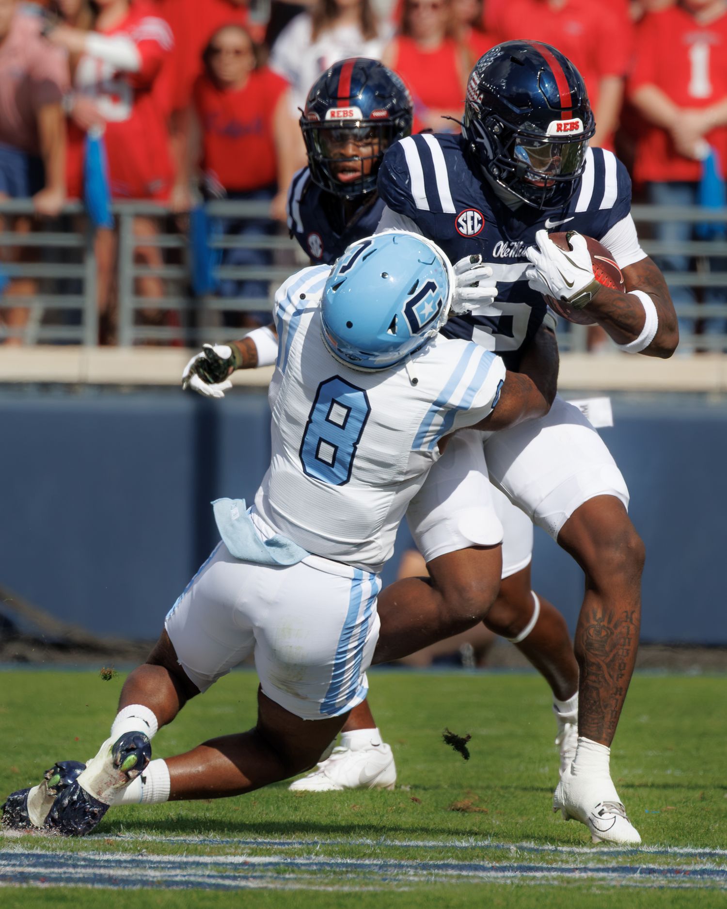 SEC football game action as Ole Miss player carries ball while Citadel defender #8 attempts tackle.