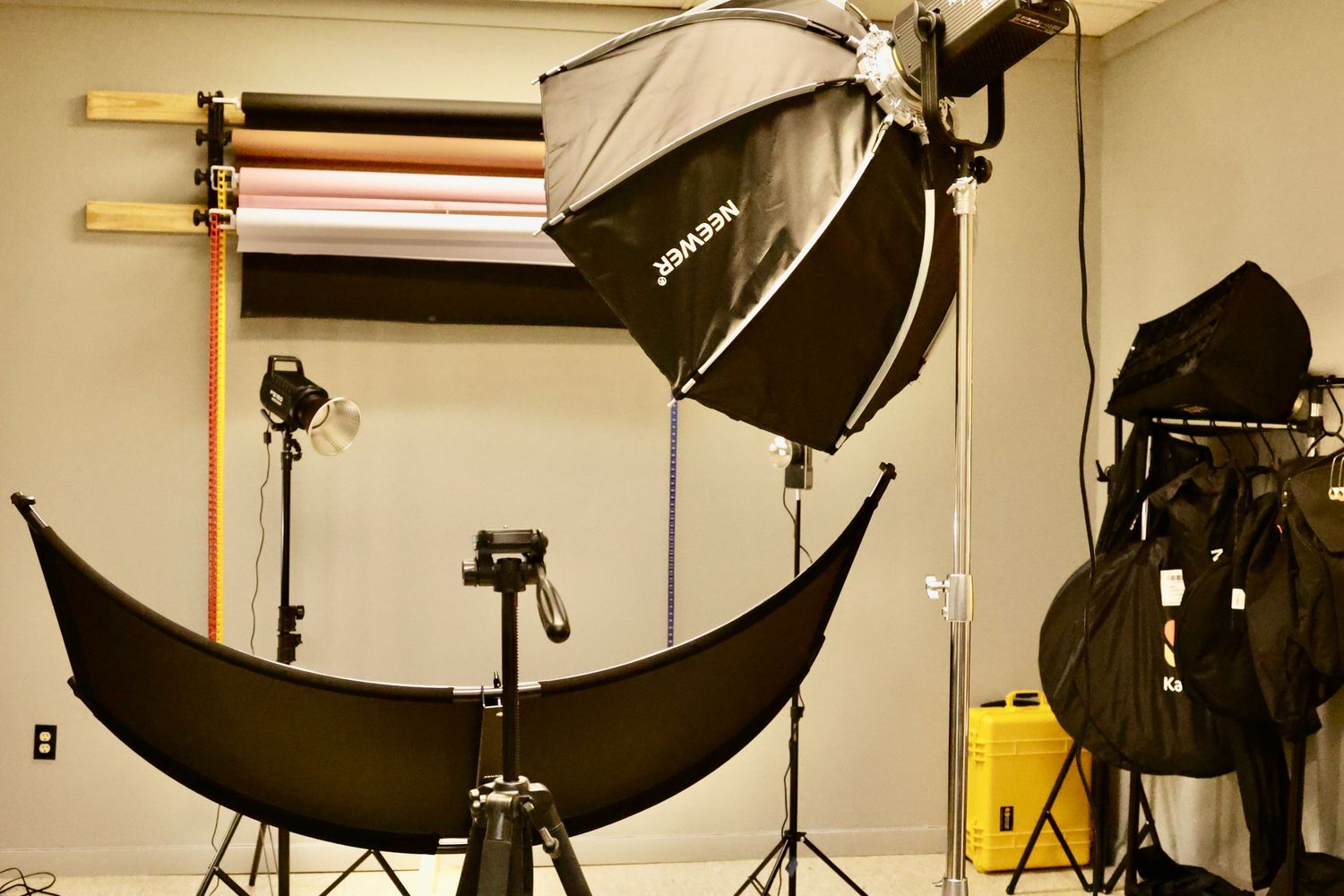 Professional photography studio setup with softbox lights, tripods, and backdrop rolls for photo shoots.