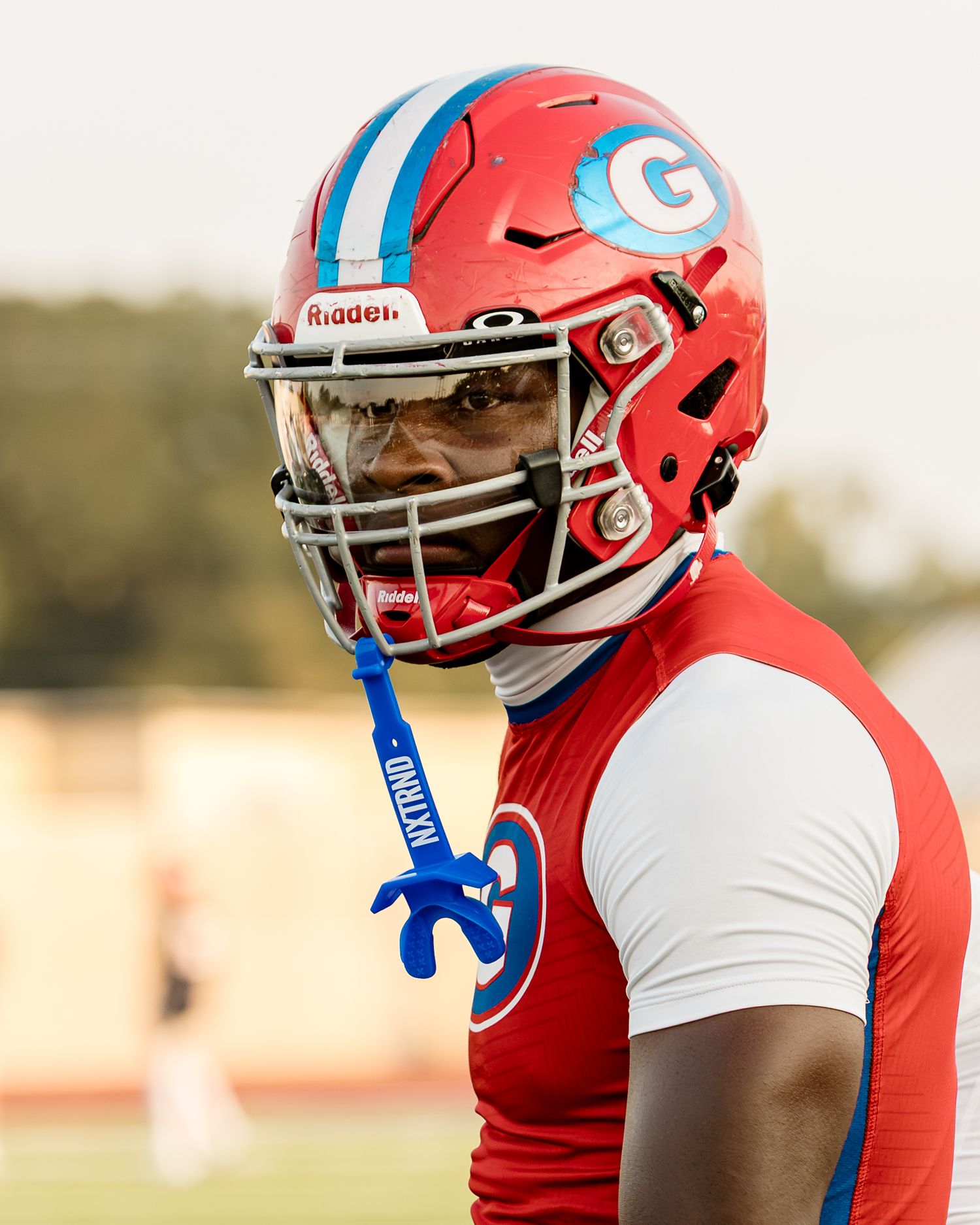 Close-up detail of red and blue football helmets with team logos during practice.