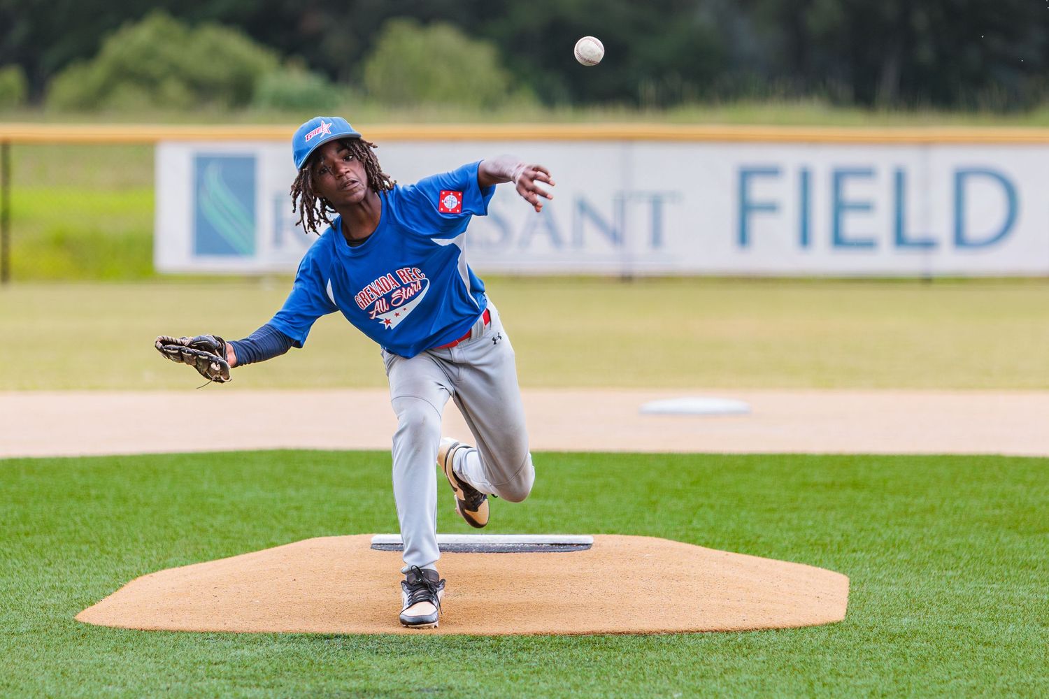 Baseball pitcher in blue uniform delivers a pitch from the mound during a game.
