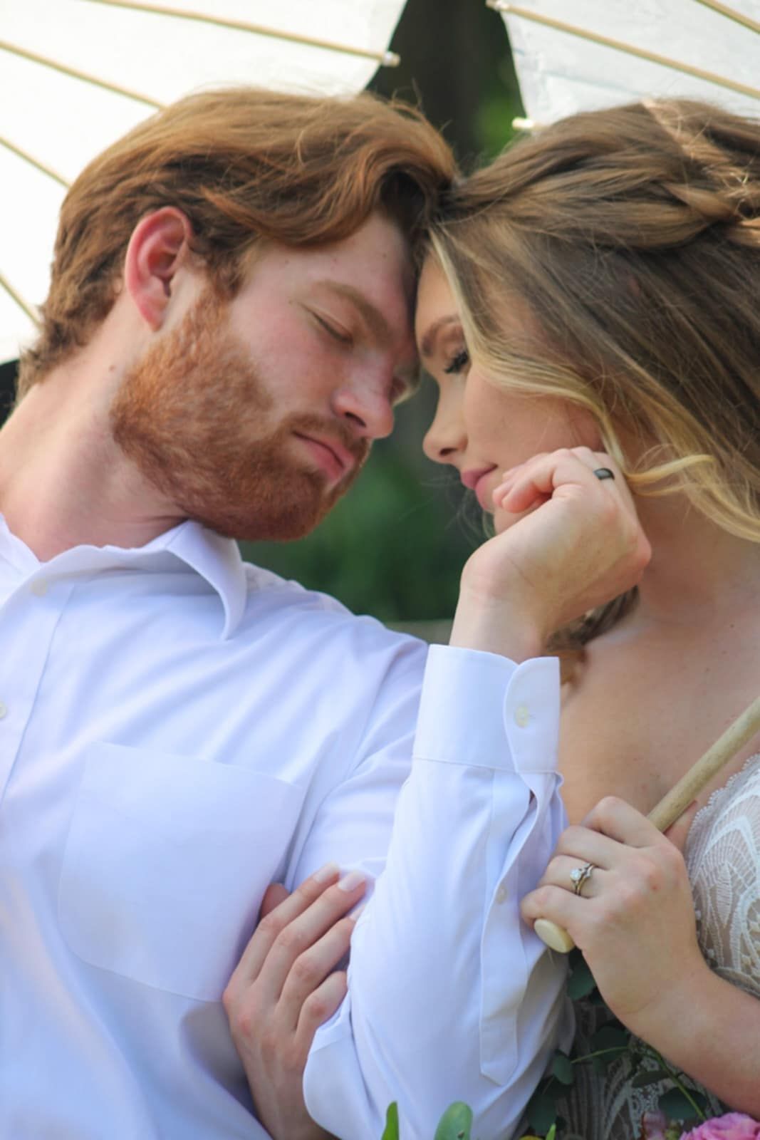 An intimate close-up moment between newlyweds in classic white attire.