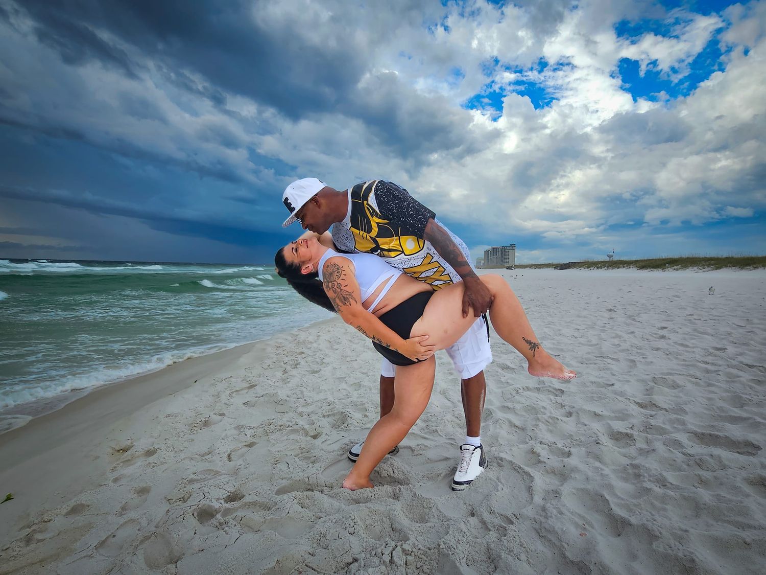 Playful beach portrait with dramatic stormy sky and ocean waves in background.