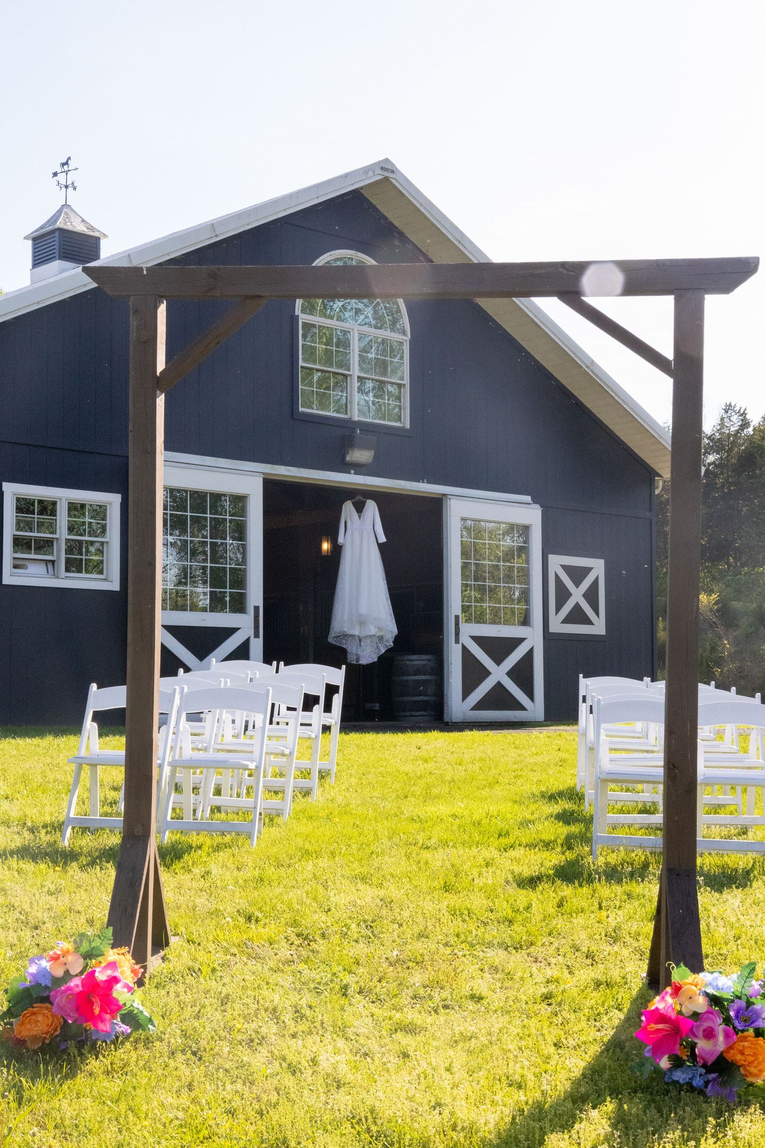 Rustic navy blue barn wedding venue with white chairs set up for outdoor ceremony.
