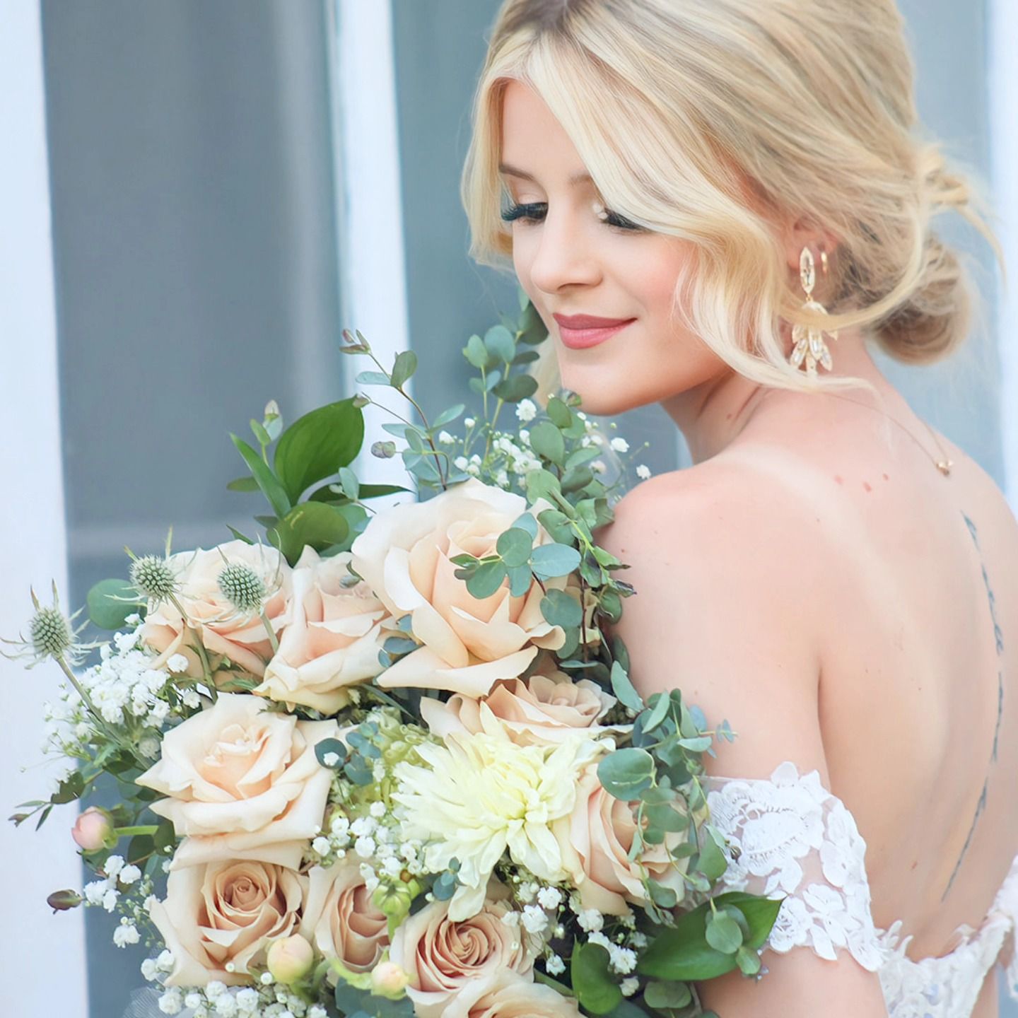 A bride holds a beautiful bouquet of peach roses and white flowers with eucalyptus.