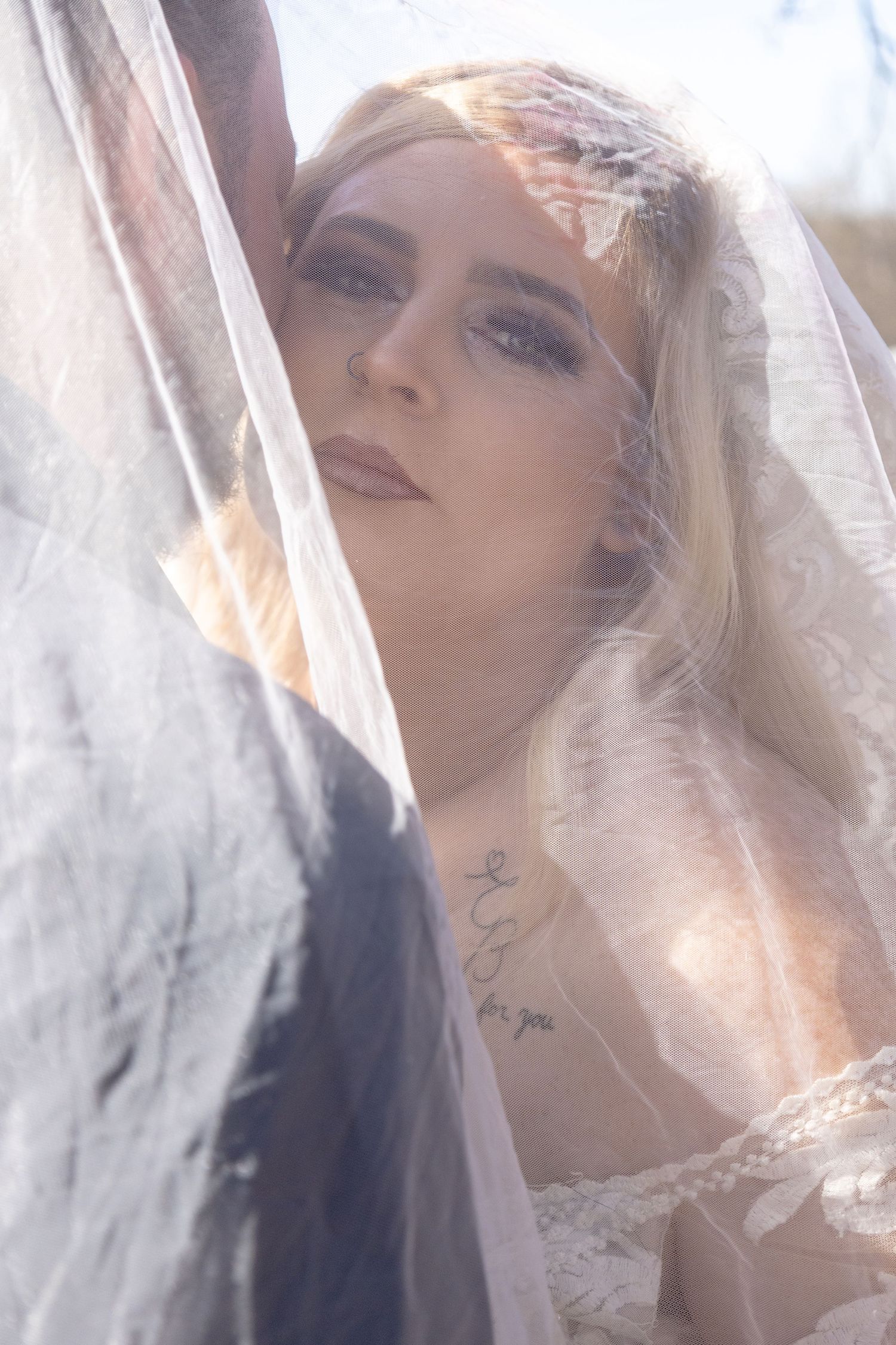A soft, ethereal bridal portrait through delicate veil fabric.