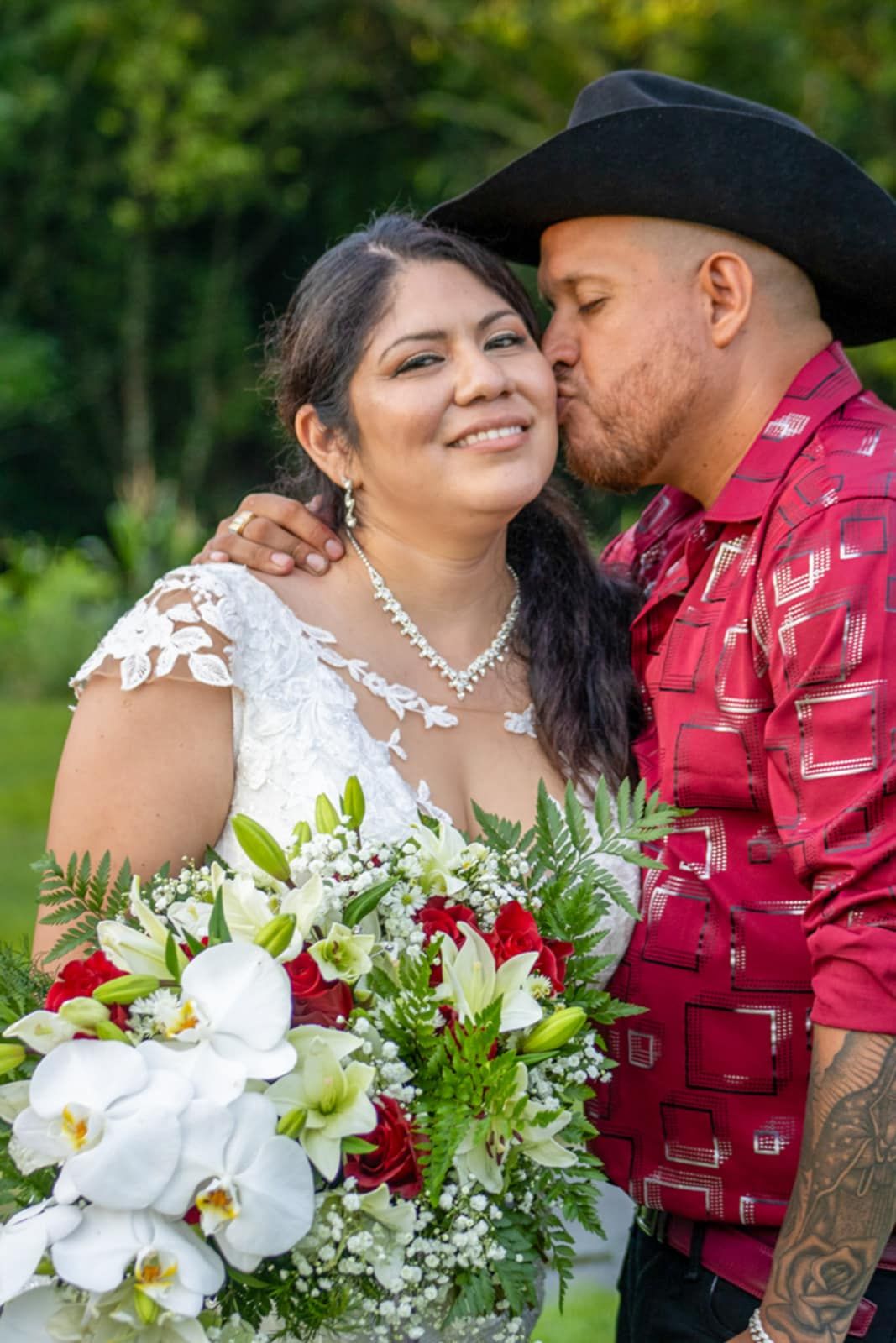 A tender moment with a beautiful bouquet of white orchids and red flowers against a garden backdrop.