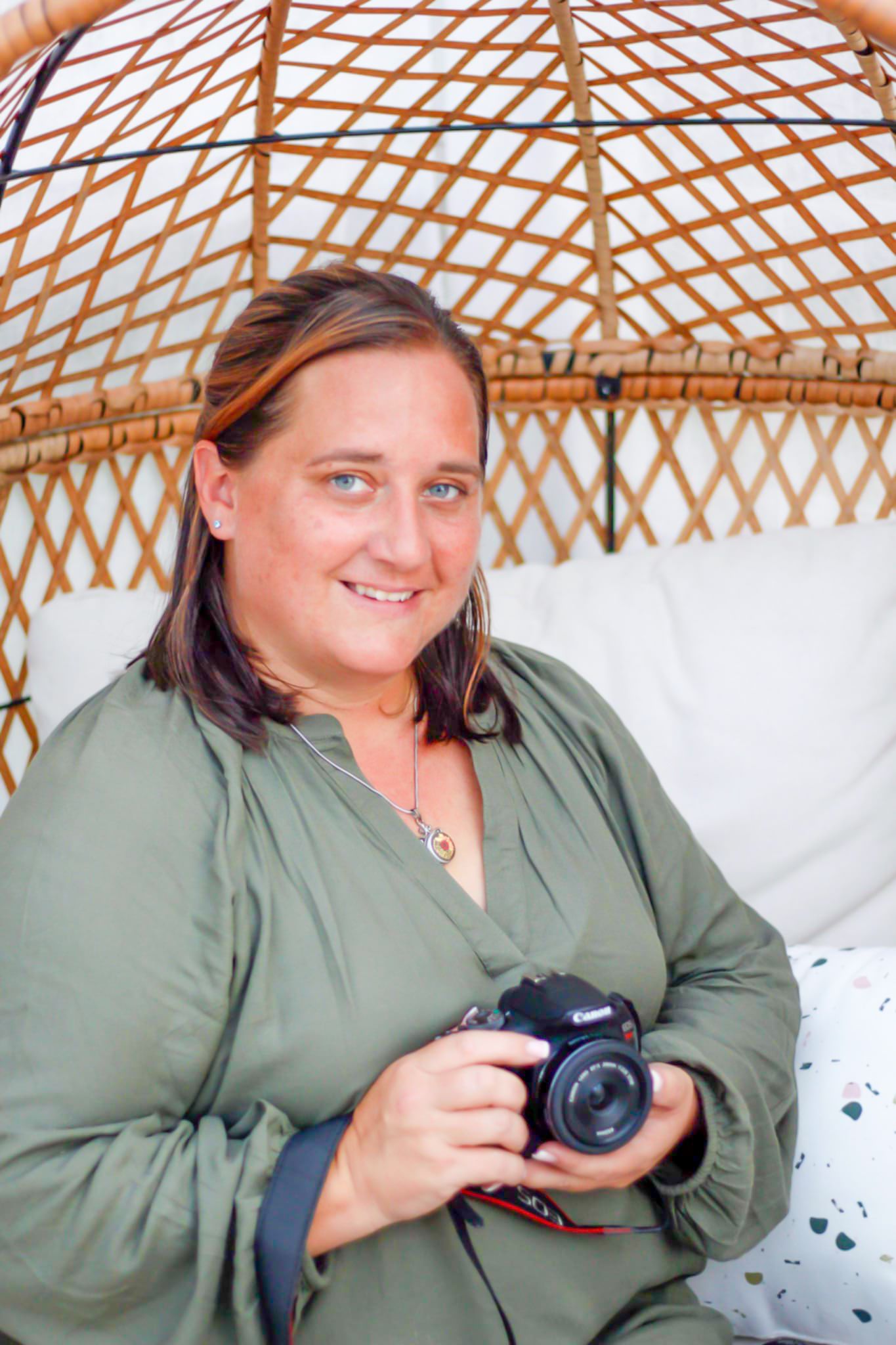 A photographer in green clothing sits in a yurt holding a professional camera.