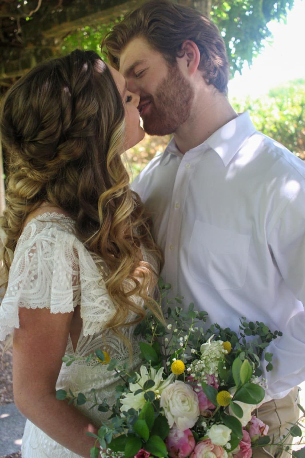 An intimate wedding portrait with greenery and a mixed pastel flower bouquet.