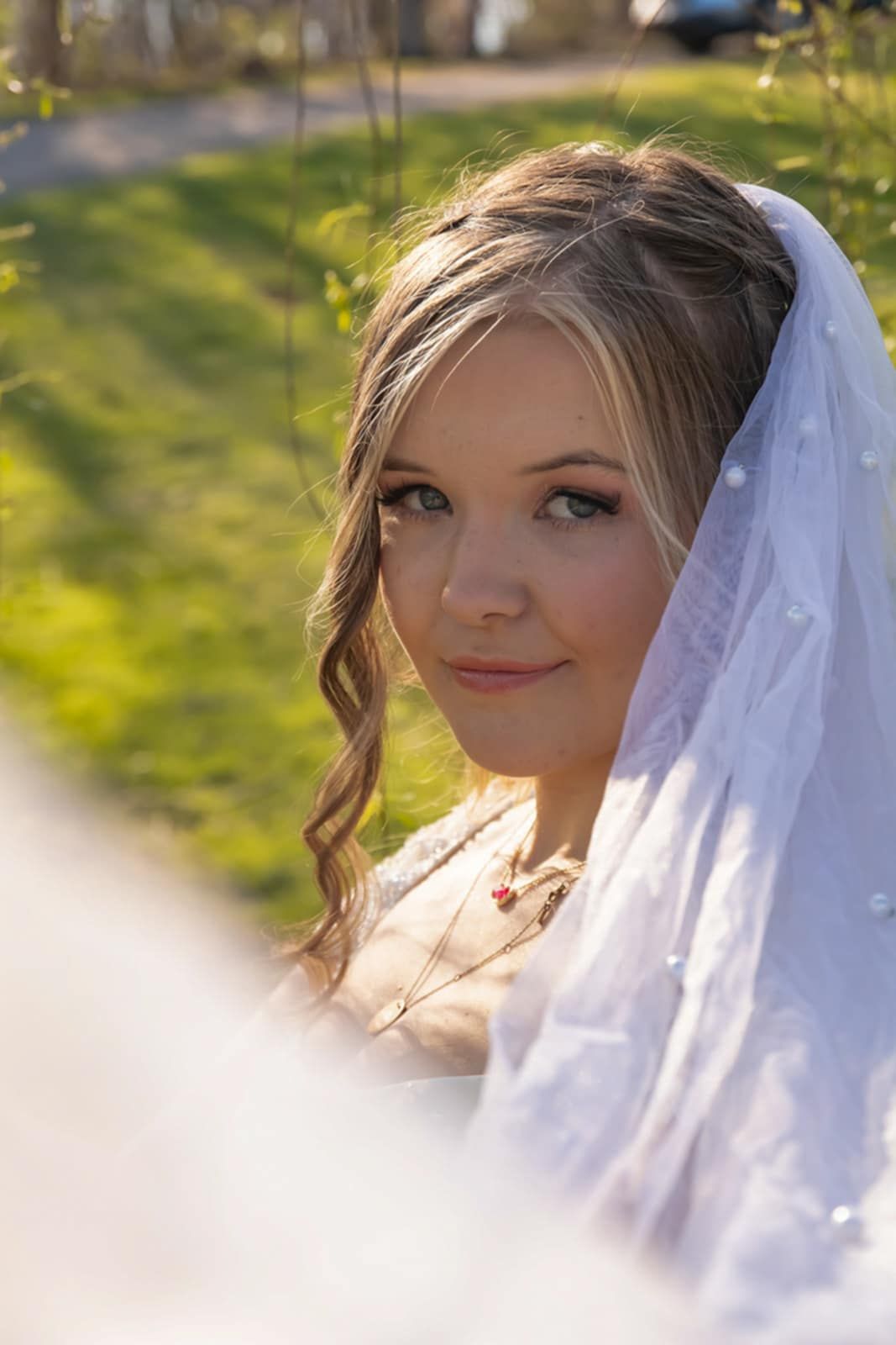 A serene bridal portrait with delicate veil and soft makeup in natural lighting.