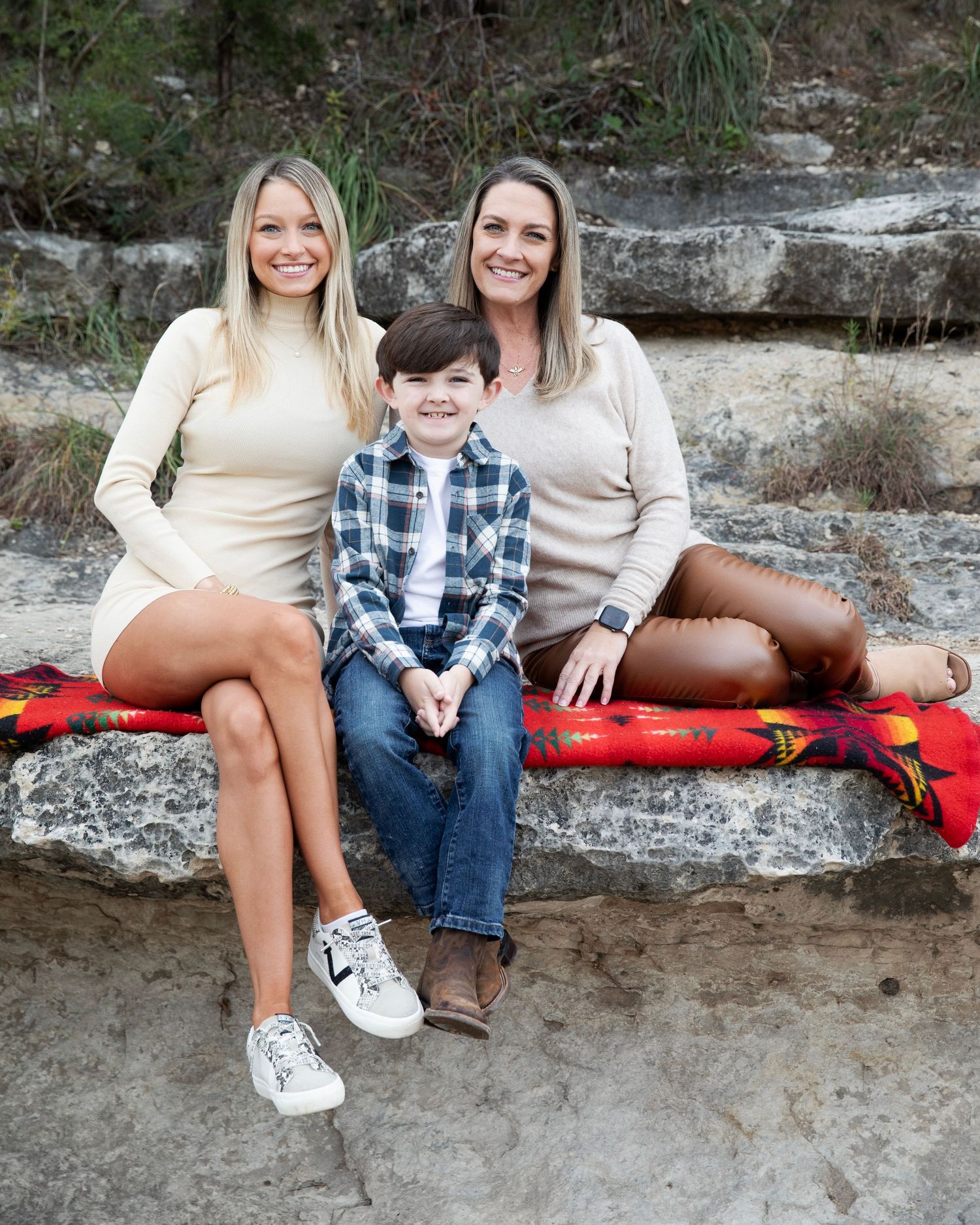 Family of three sit together on a rocky ledge at Bull Creek, in North Austin.