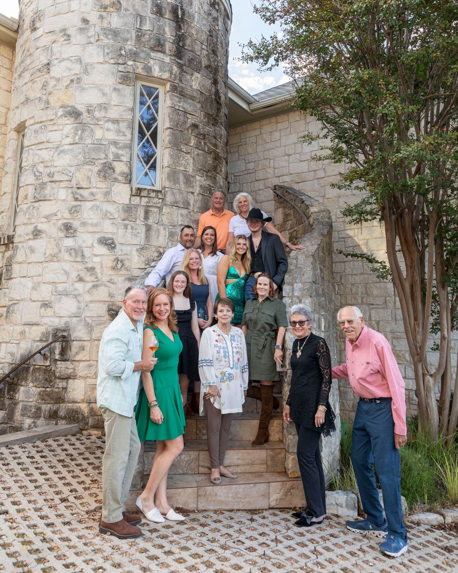A group of people gathered on stone steps in front of a castle-like building with a turret and diamond-pane window.