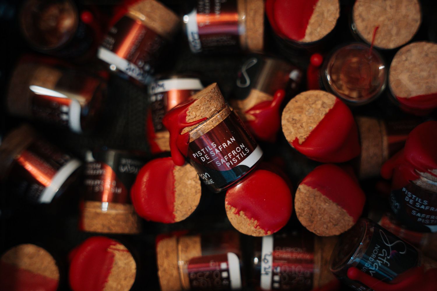 Small cork-sealed jam jars with red wax tops arranged in a rustic overhead display.