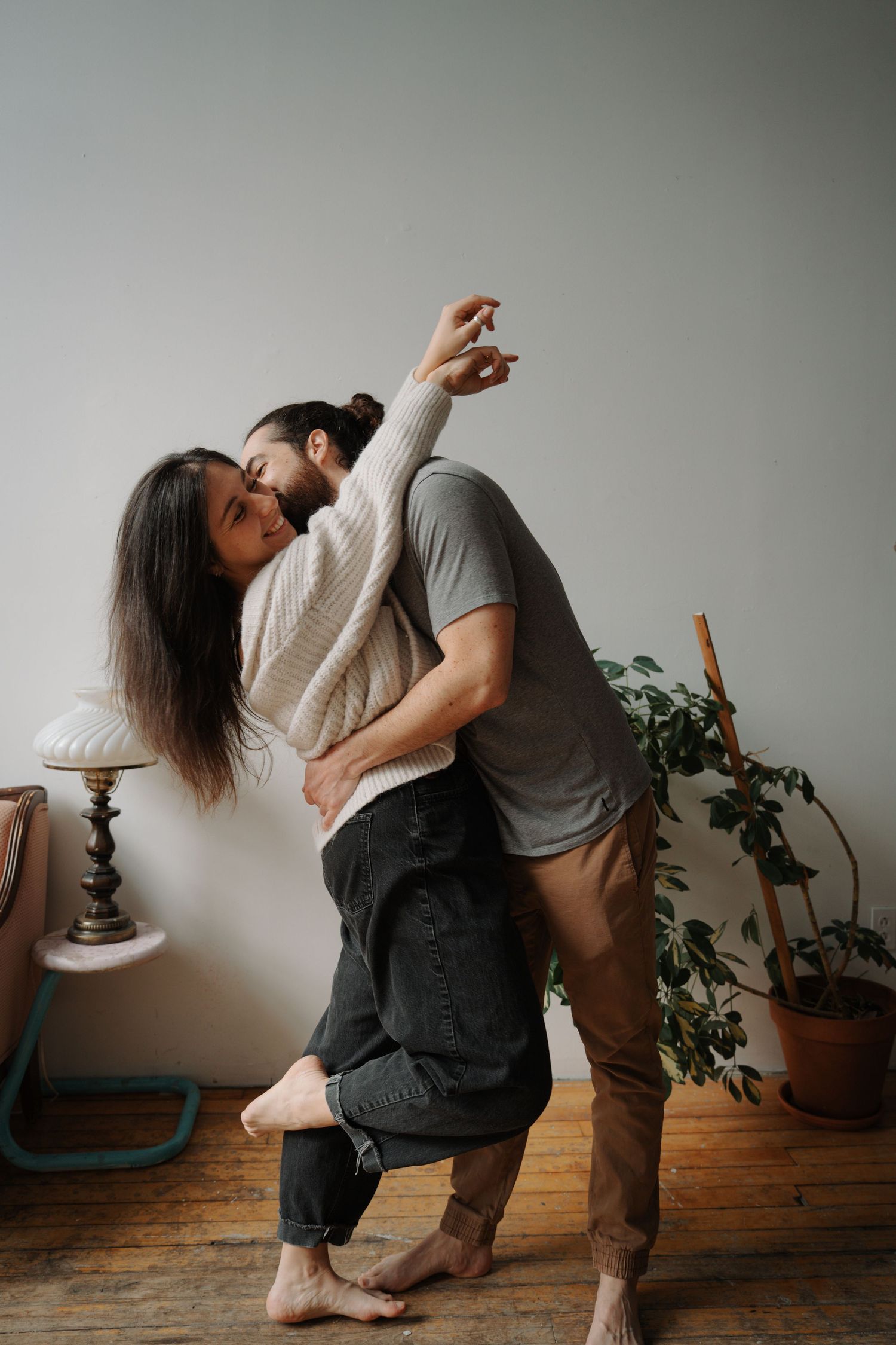 Couple dancing together barefoot indoors, man dipping woman gracefully in a warmly decorated living room.