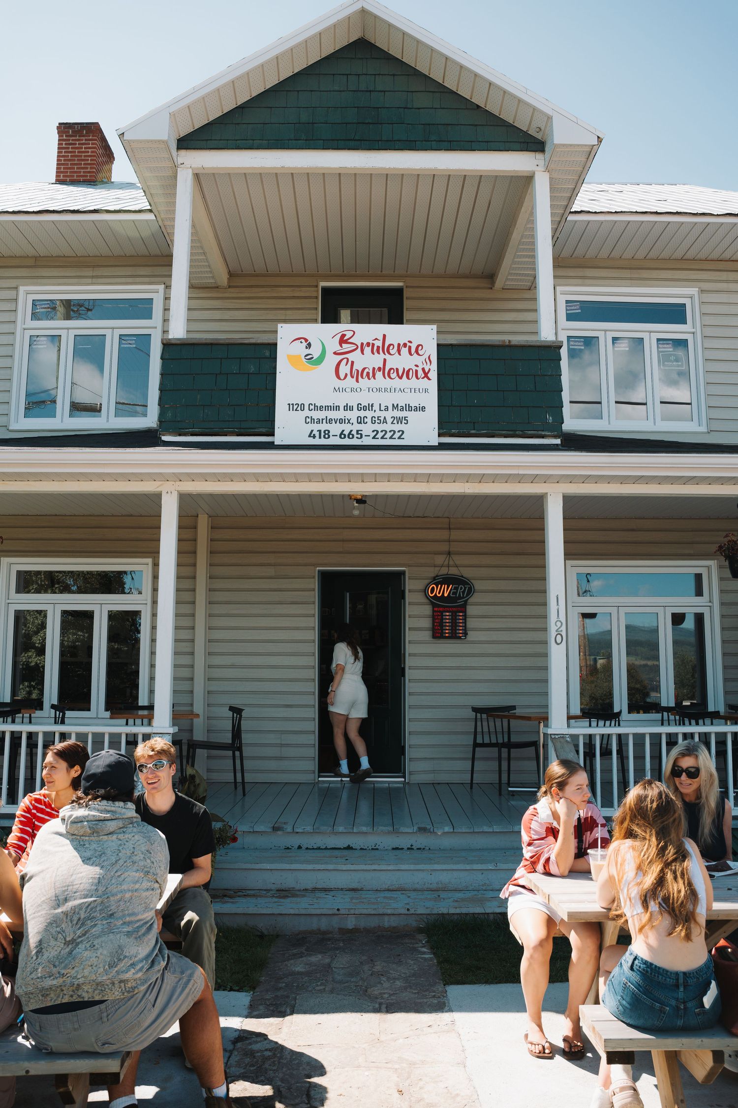 Customers sitting outside Broderie Charlevoix shop on a sunny summer day.
