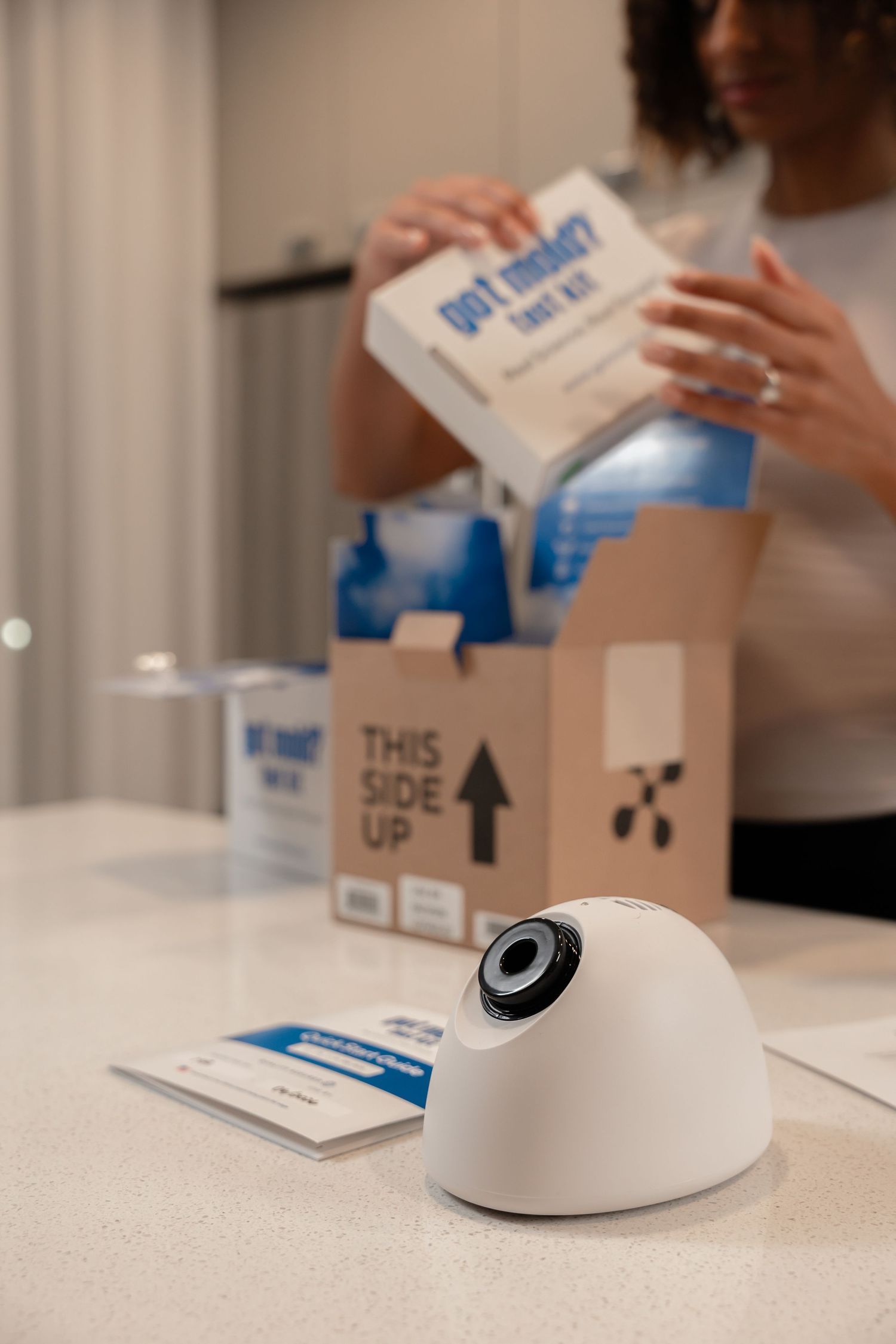 Woman unpacking a Got Mold test kit box on a kitchen counter with air sampling cassette in foreground.