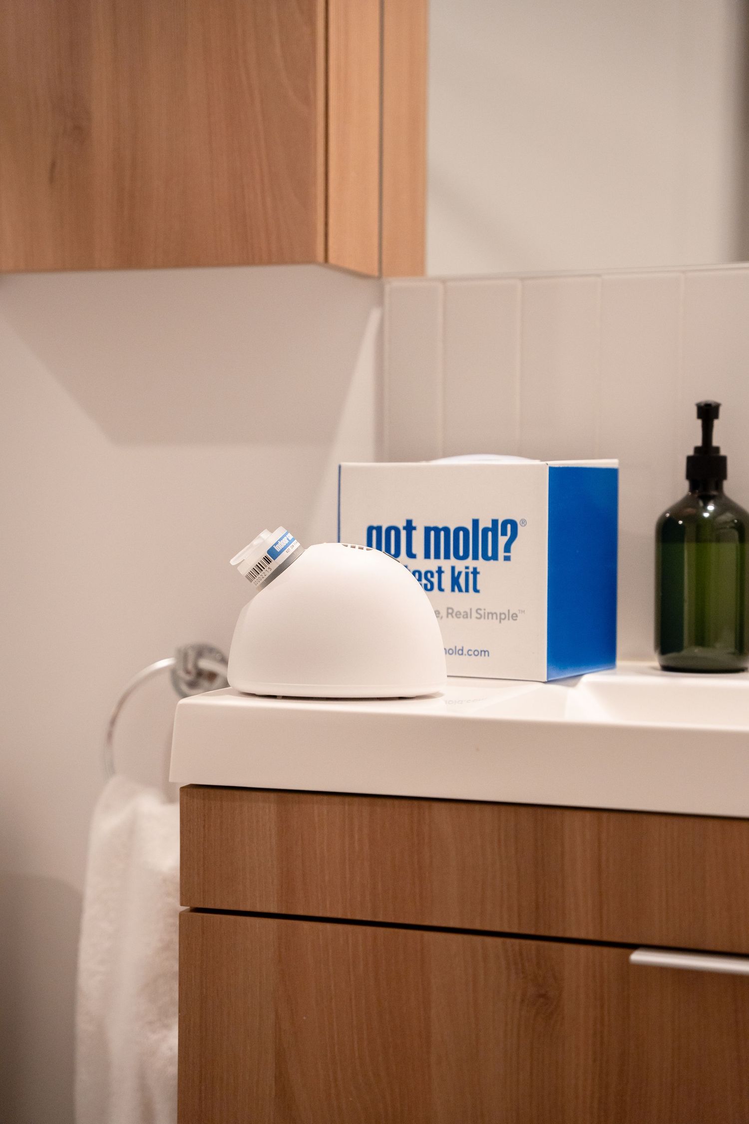 Got Mold test kit box and white air sampling device on a modern bathroom vanity countertop.