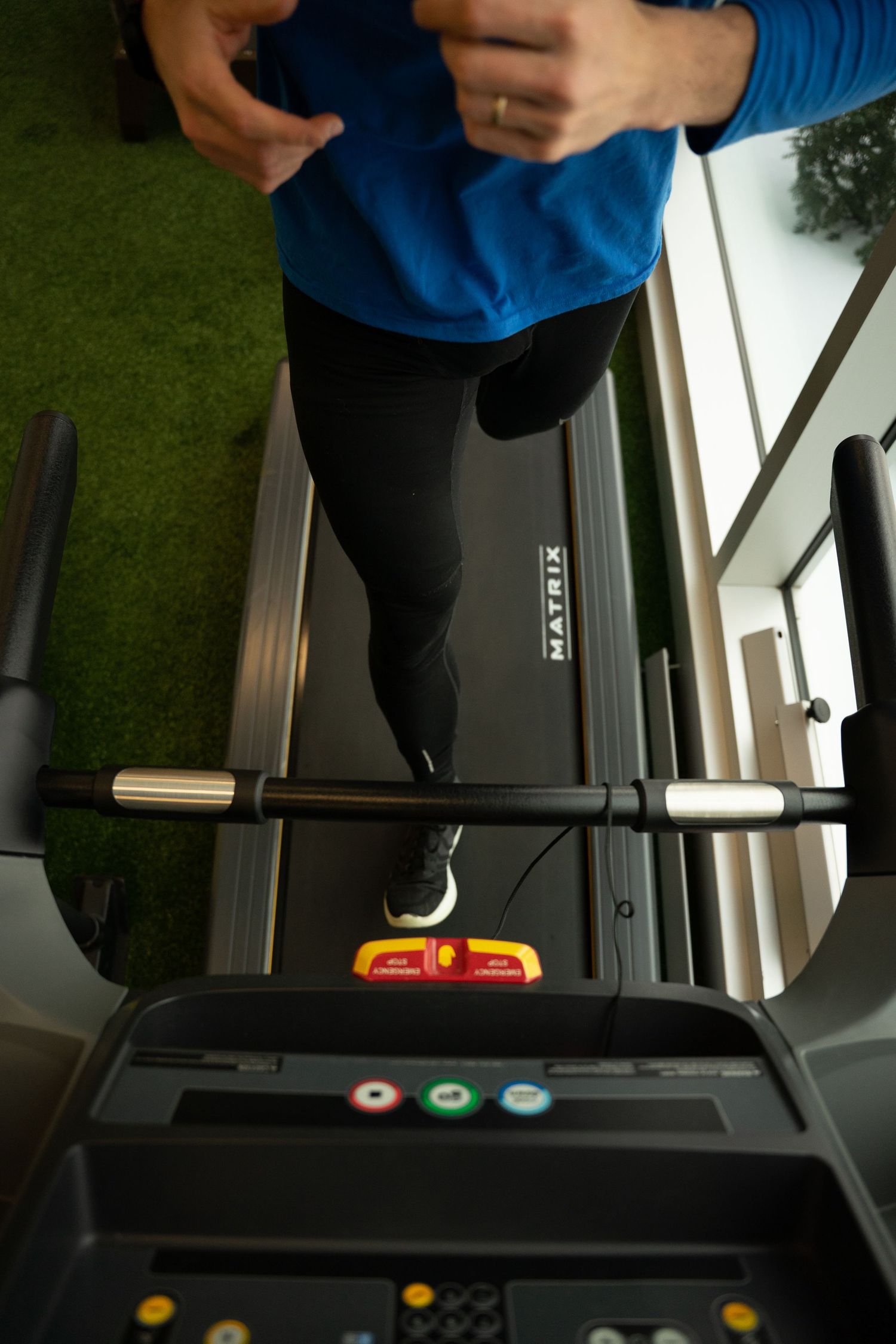 Top-down view of a person in blue running on a Matrix treadmill during an indoor workout.