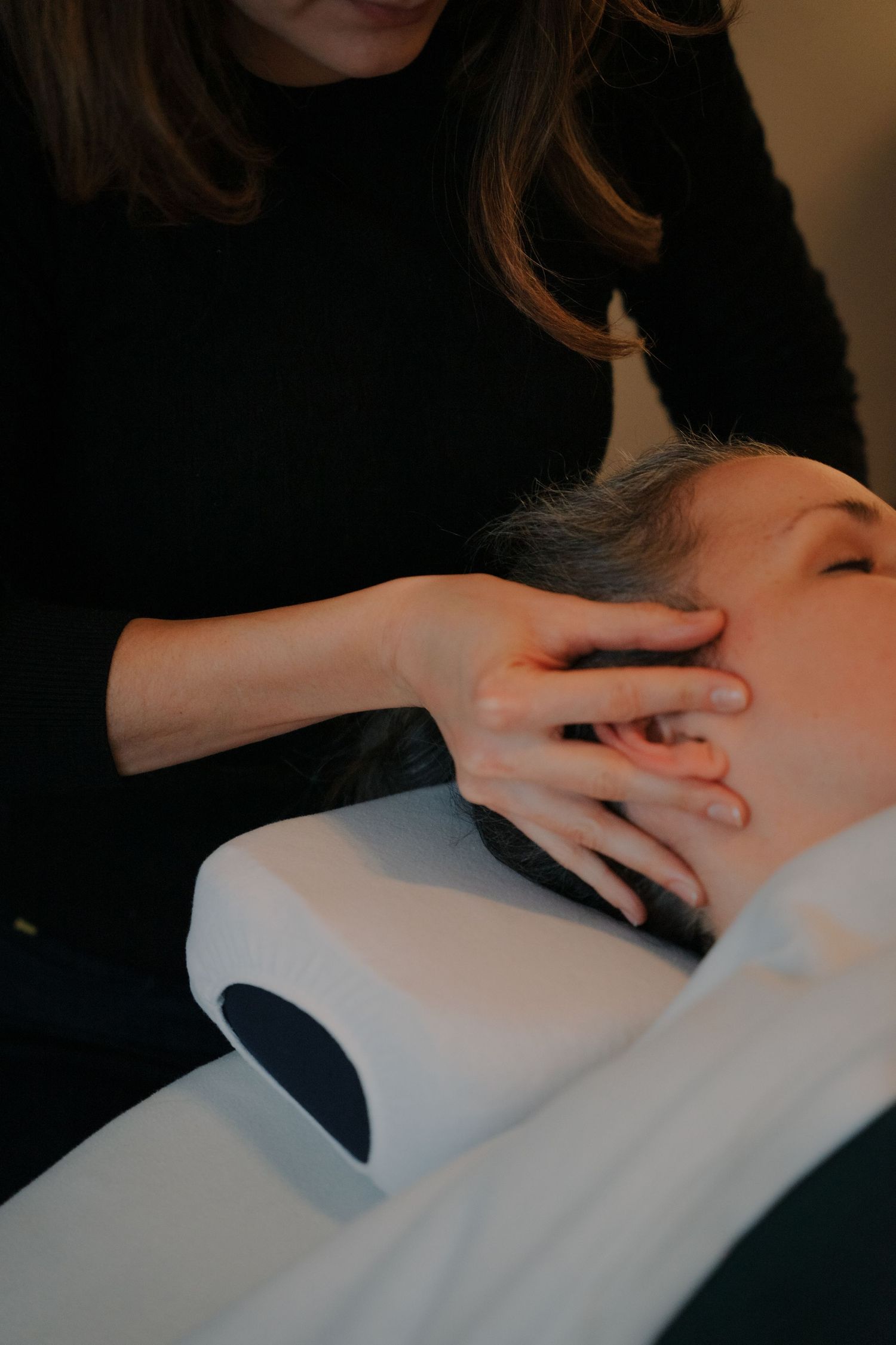 Massage therapist performing a relaxing head and scalp massage on a reclining client.
