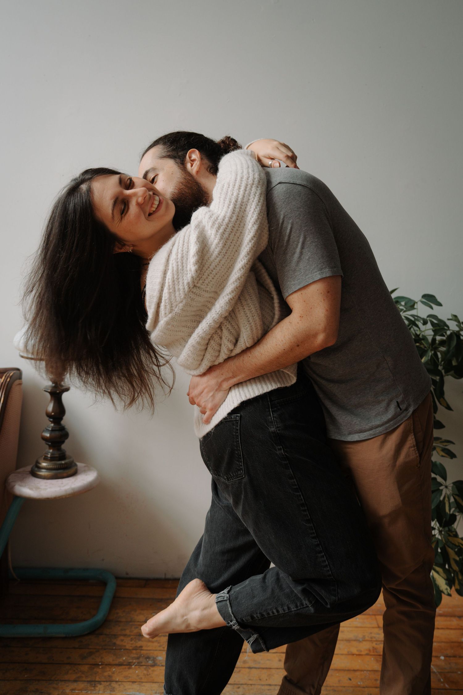 Joyful couple embracing and laughing together in a warmly decorated indoor space.