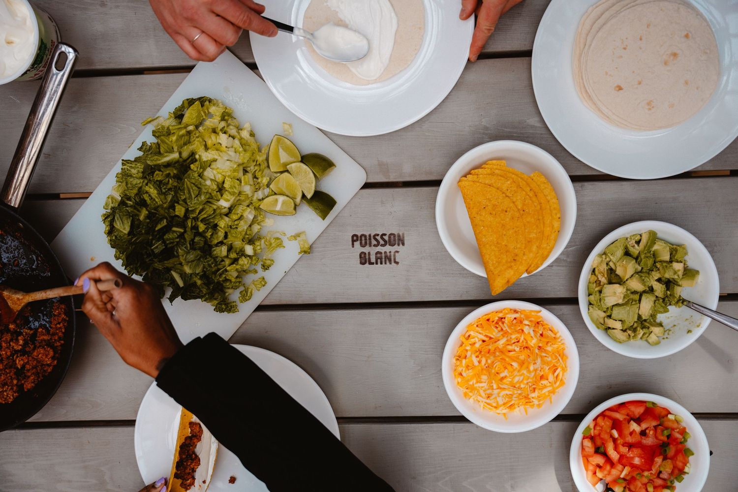 Overhead view of fresh taco ingredients including lettuce, cheese, salsa, and sour cream on a table.