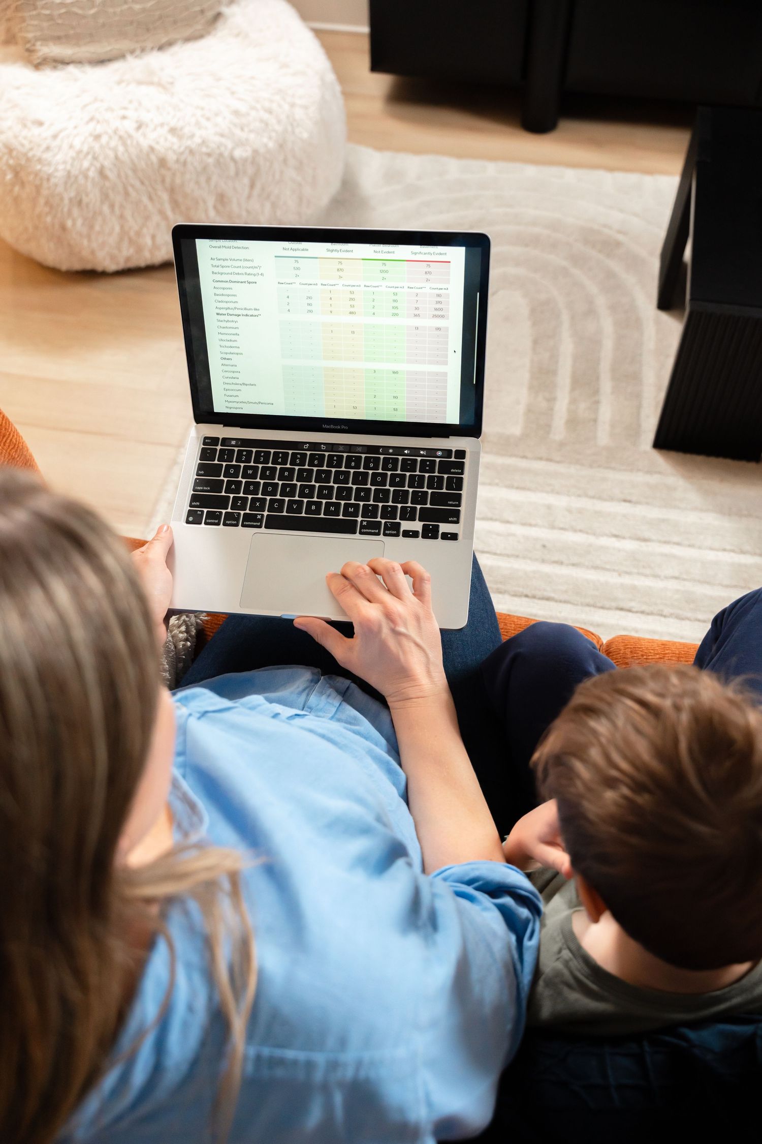 Mother and child reviewing mold test results on laptop computer while sitting on sofa.