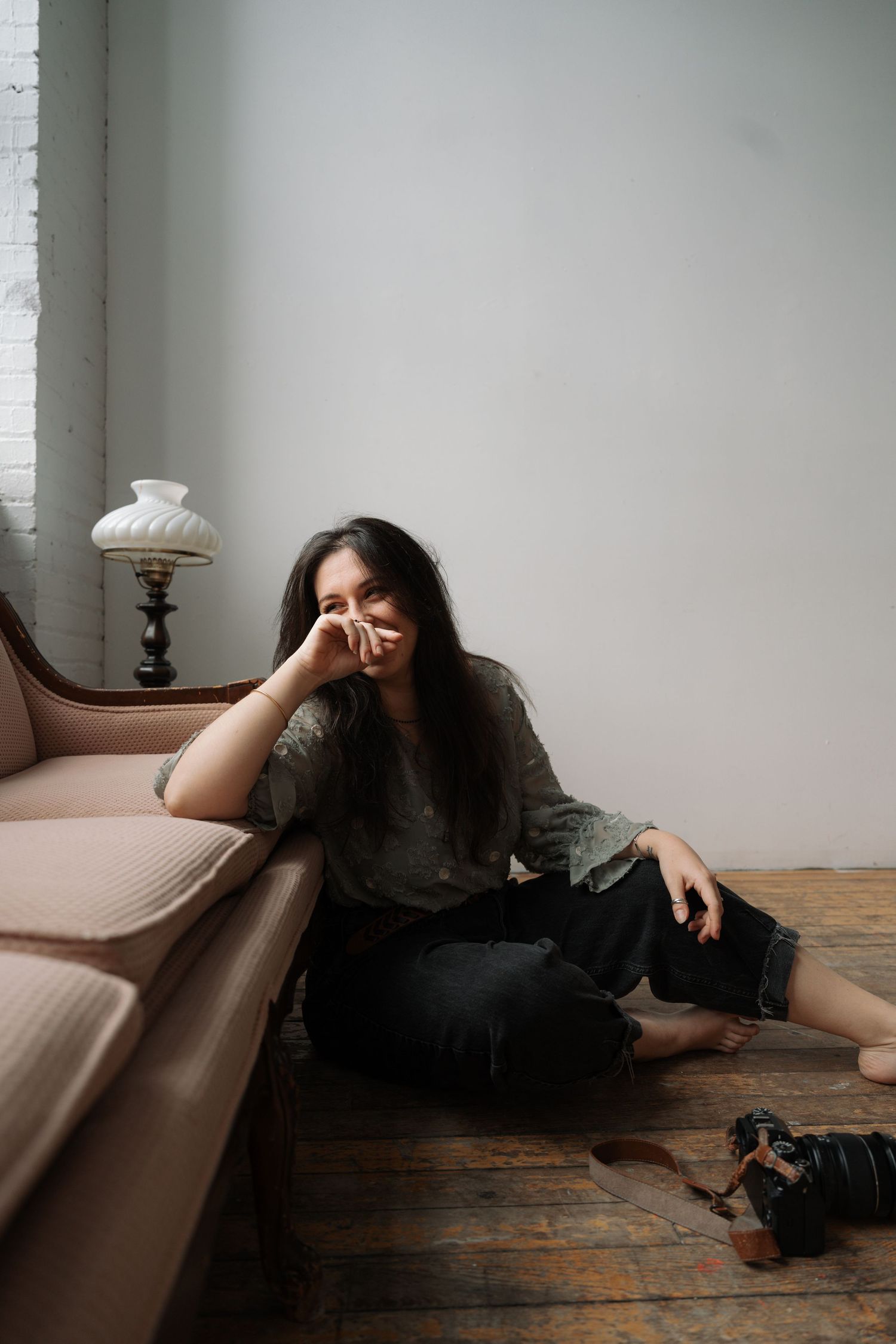 Relaxed dark-haired woman sitting on floor leaning against vintage sofa.