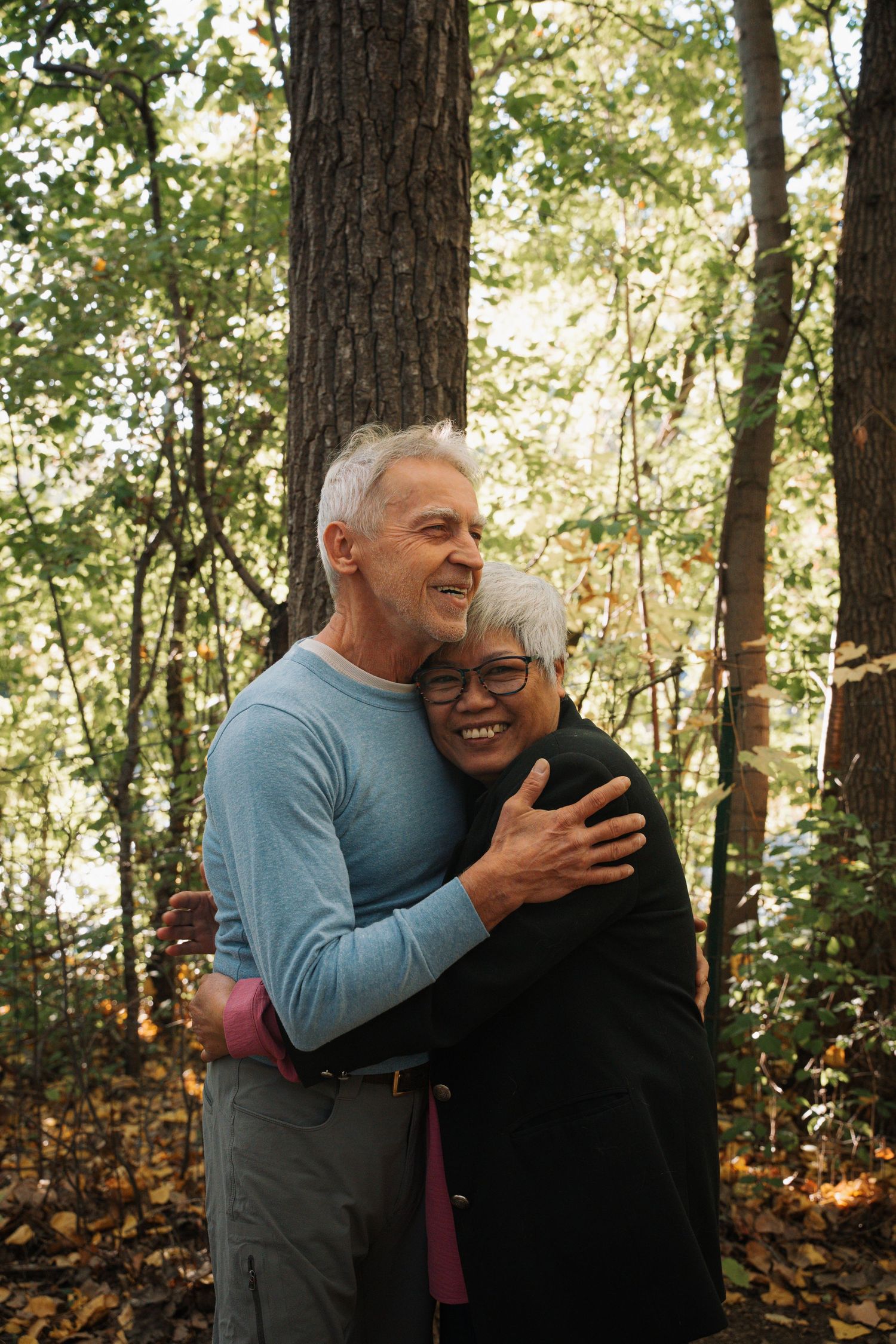 Happy senior couple embracing and smiling in autumn forest setting.