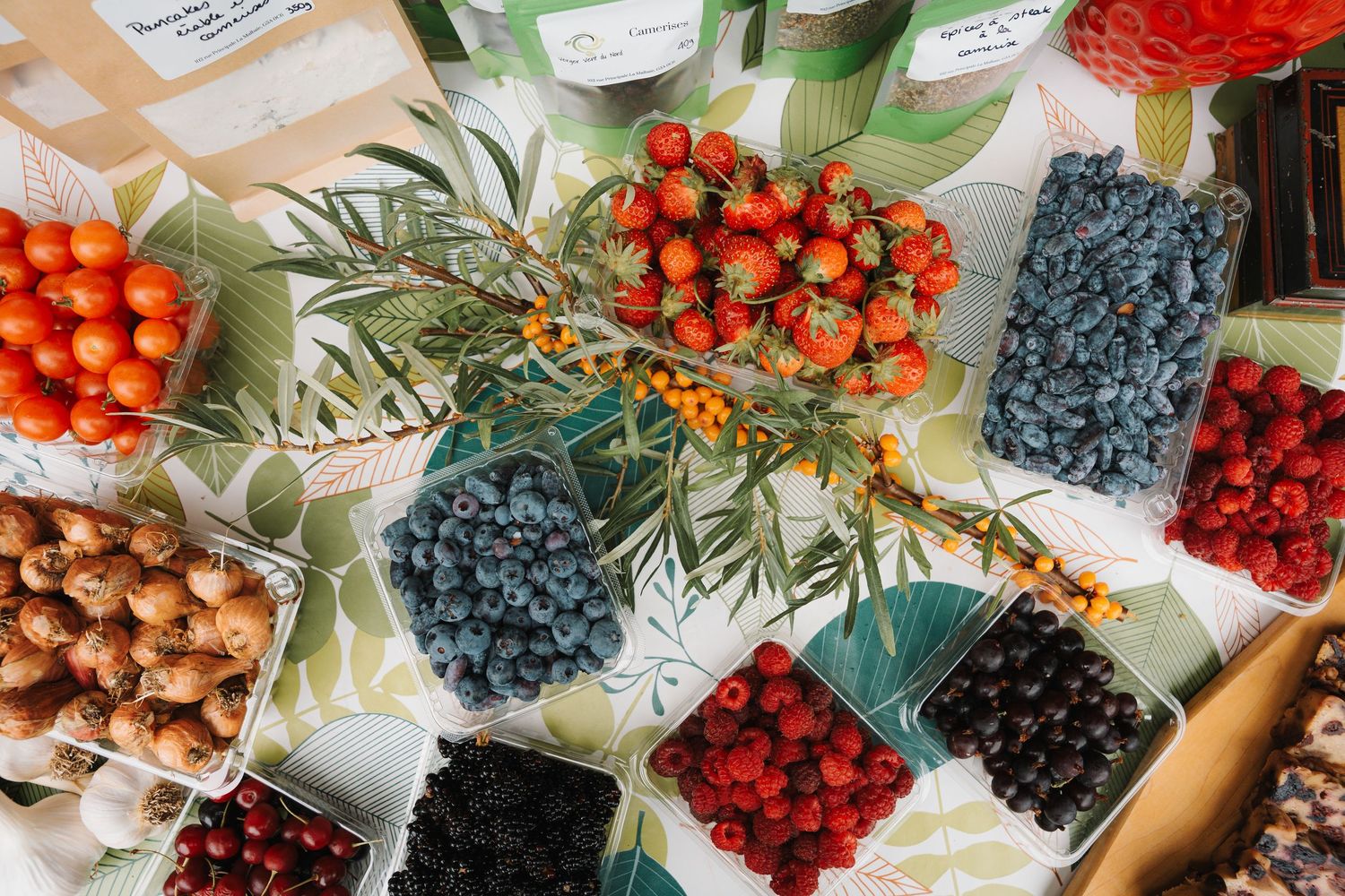 Colorful assortment of fresh berries and fruits displayed in containers at a market stall.