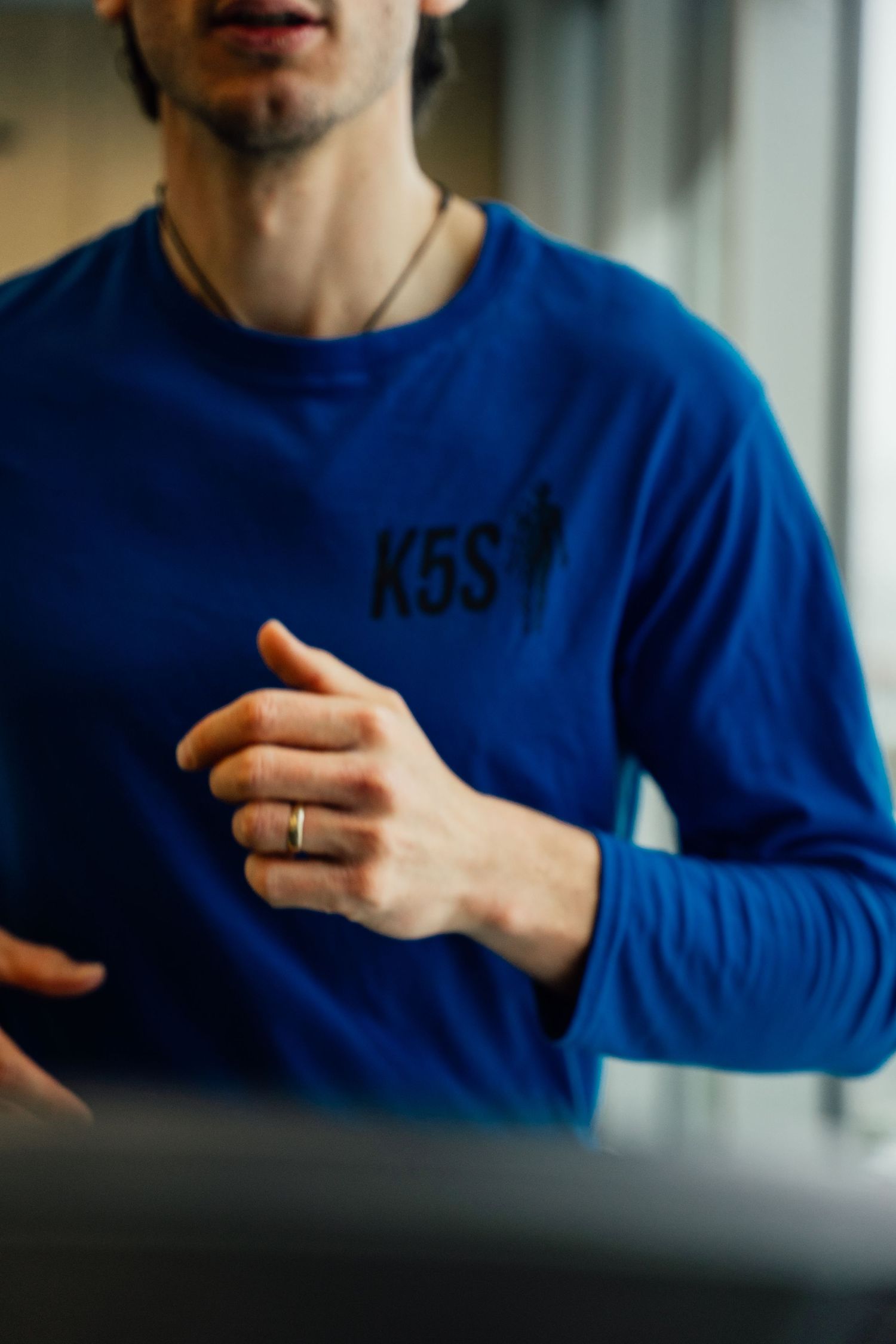 A man in a blue K5S long-sleeve shirt runs on a treadmill during an indoor workout session.