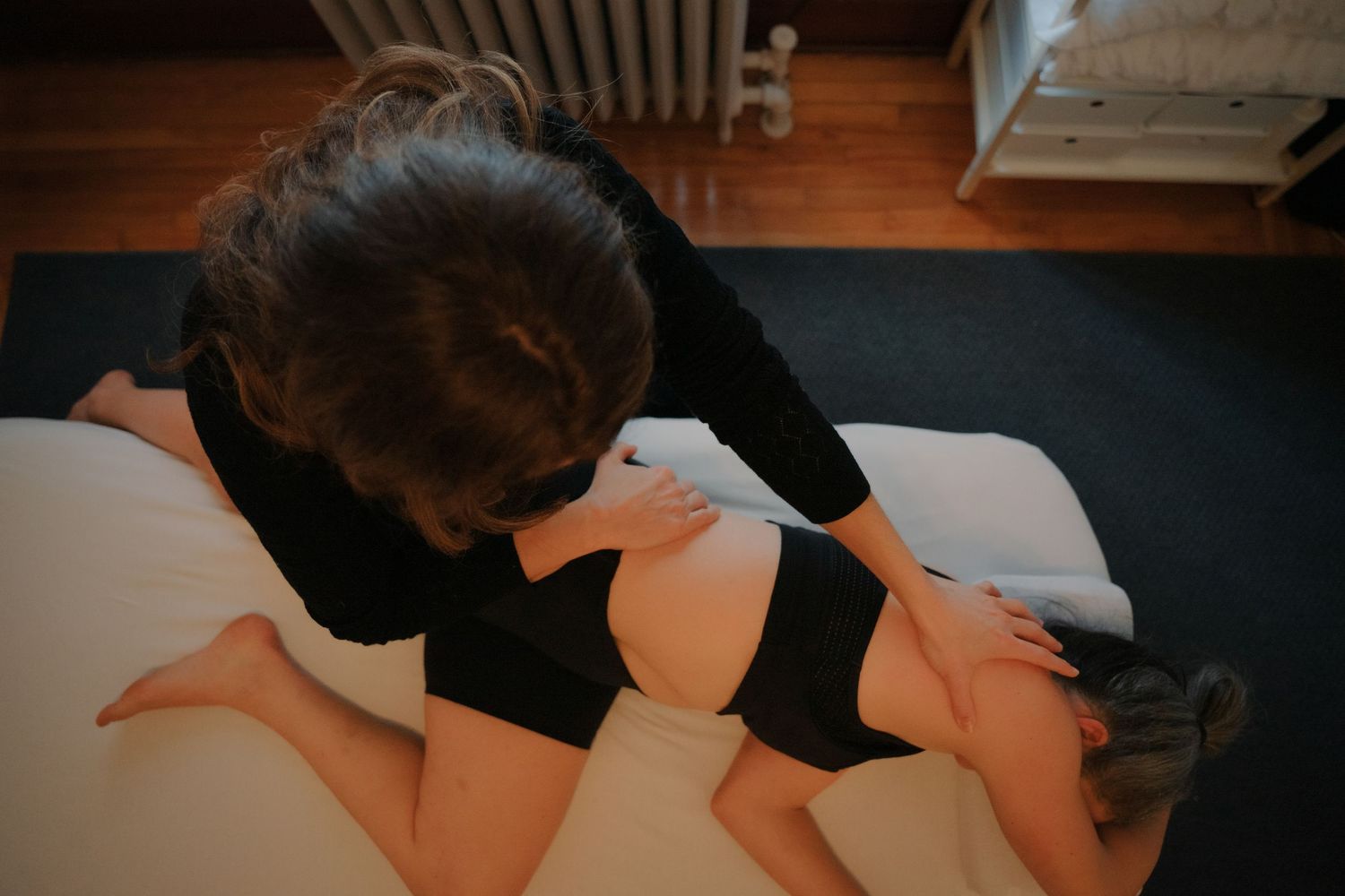 Overhead view of massage therapist performing upper back and shoulder massage on prone client.