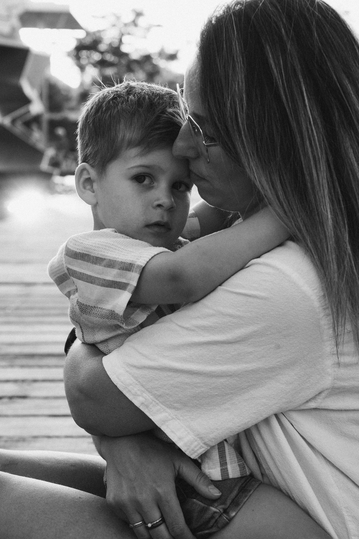 Black and white photo of a mother tenderly embracing her young son, their foreheads touching in a loving moment.