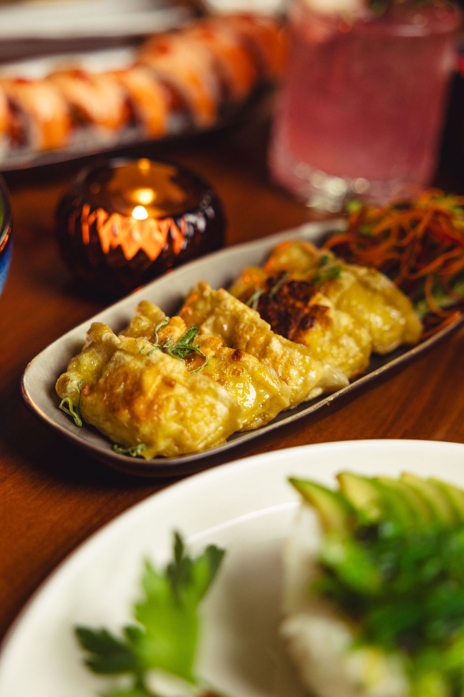 Elegantly plated baked seafood dish with melted cheese and garnish on a dark plate.