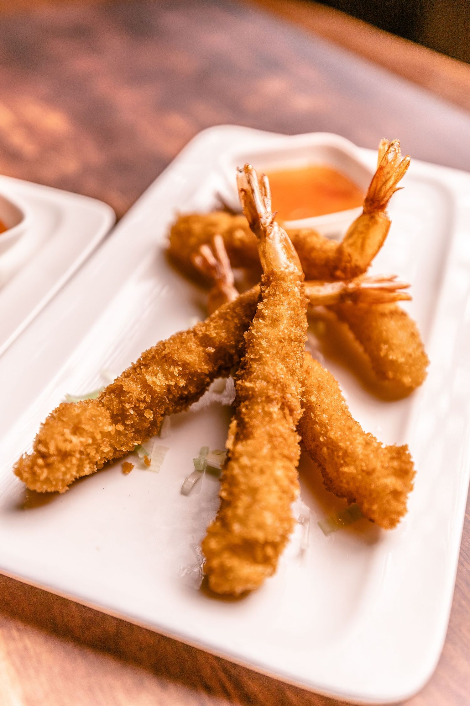Golden crispy breaded shrimp arranged on white plates in sequence.
