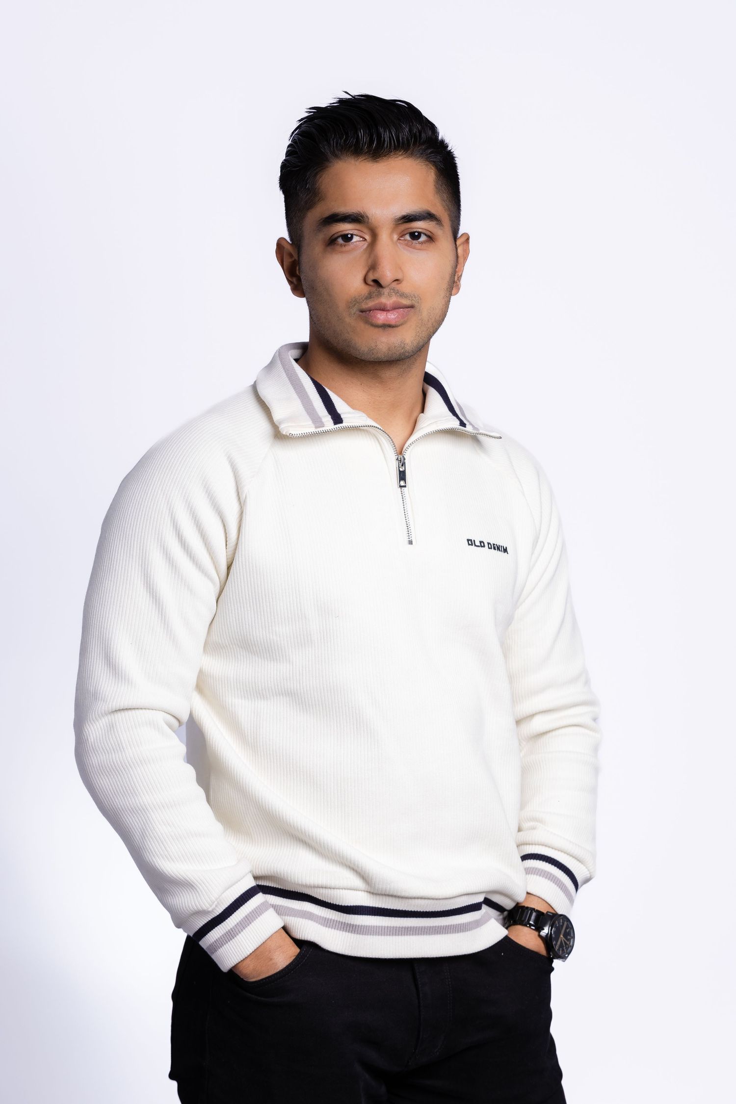 Casual portrait of someone wearing a white polo sweater against a bright white background.