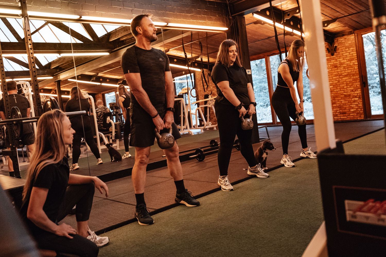 Group fitness class participants working out in a spacious industrial-style gym.