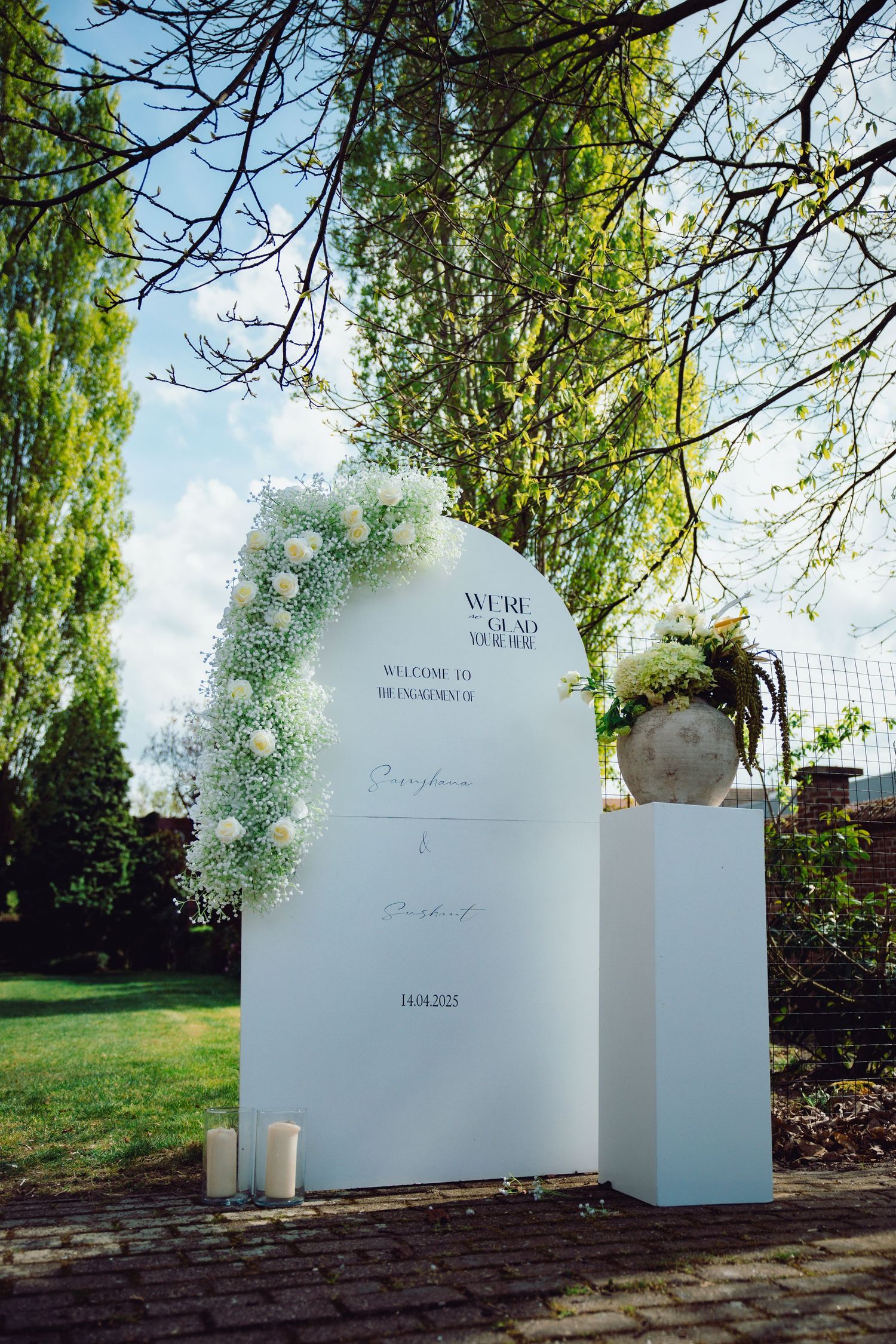 White curved memorial or architectural elements arranged in a garden setting against a blue sky and trees.